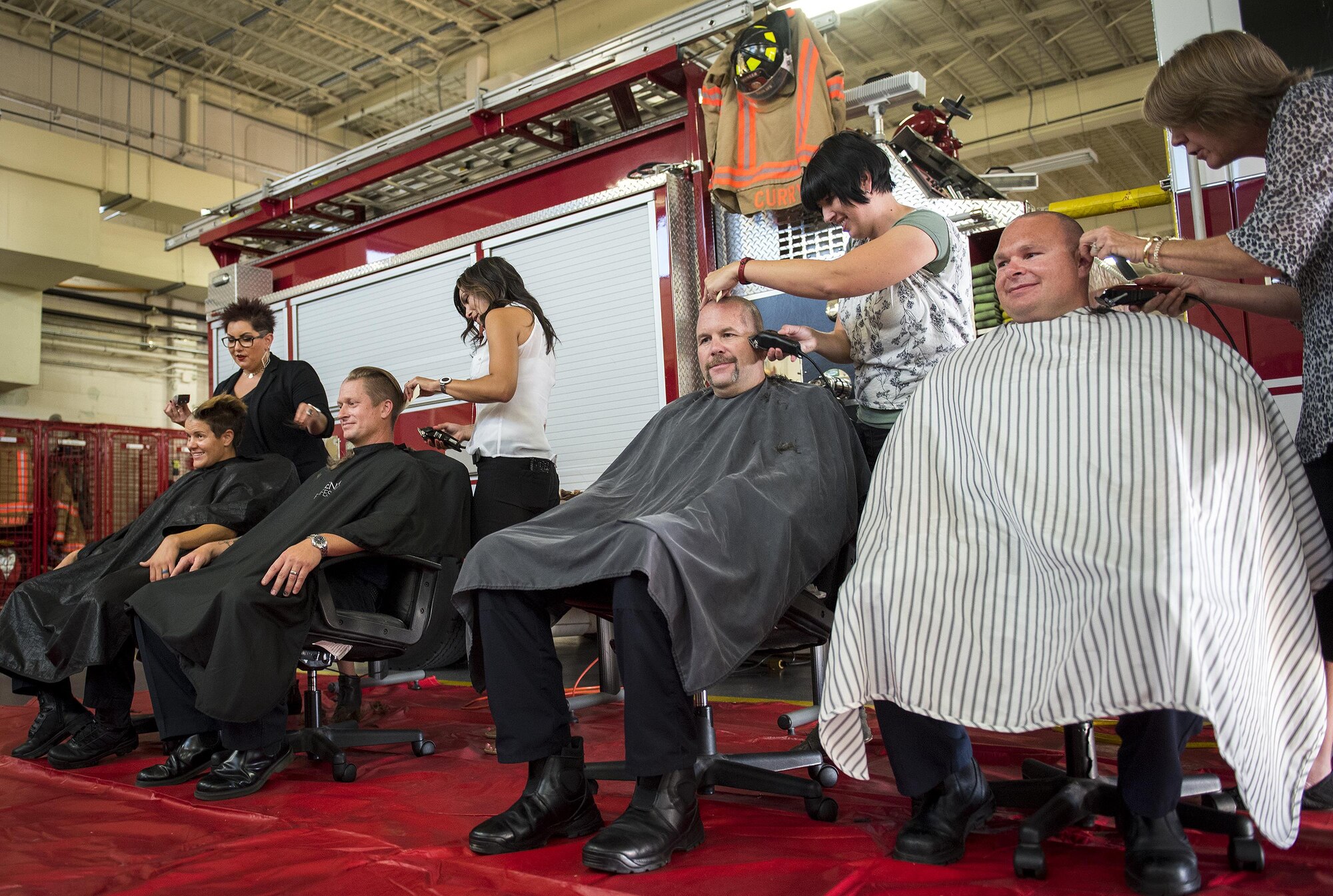 A group of firefighters receive a very close shave June 8 at Eglin Air Force Base, Fla.  Approximately 20 firefighters shaved their heads to raise awareness and funds for their crew mate, Terrance Curry, whose battled cancer continuously for 11 months.  (U.S. Air Force photo/Samuel King Jr.)