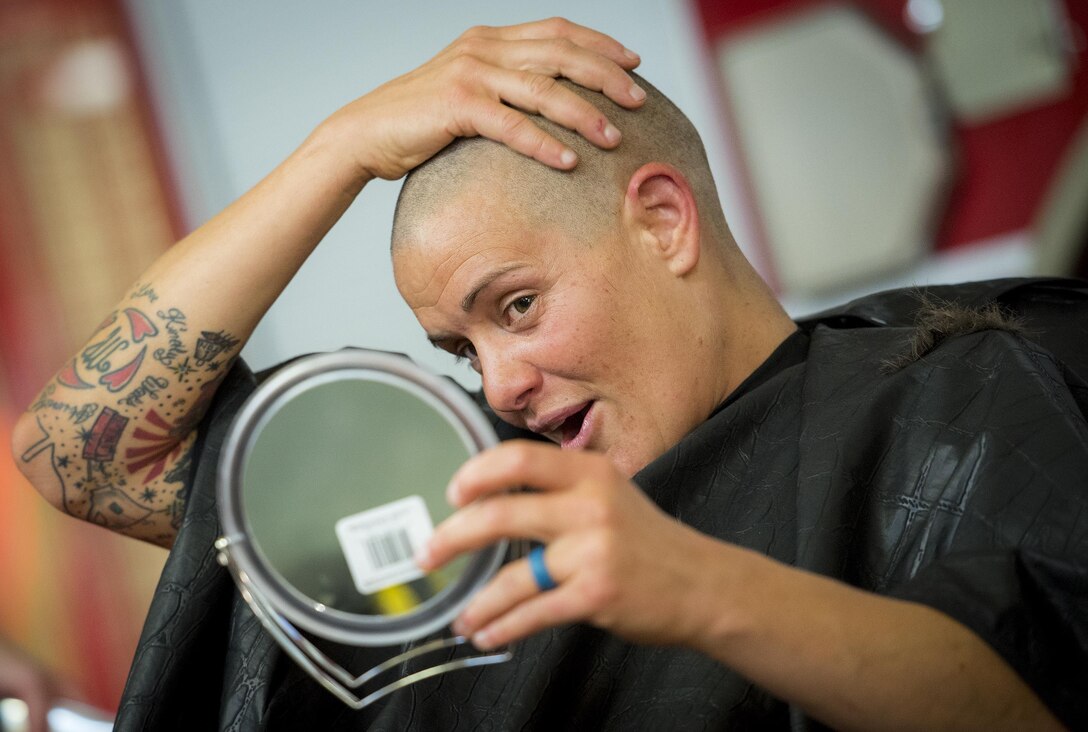 Amber Turek, a 96th Test Wing firefighter, checks out her skull after having her head shaved June 8 at Eglin Air Force Base, Fla.  Approximately 20 firefighters shaved their heads to raise awareness and funds for their crew mate, Terrance Curry, whose battled cancer continuously for 11 months.  (U.S. Air Force photo/Samuel King Jr.)