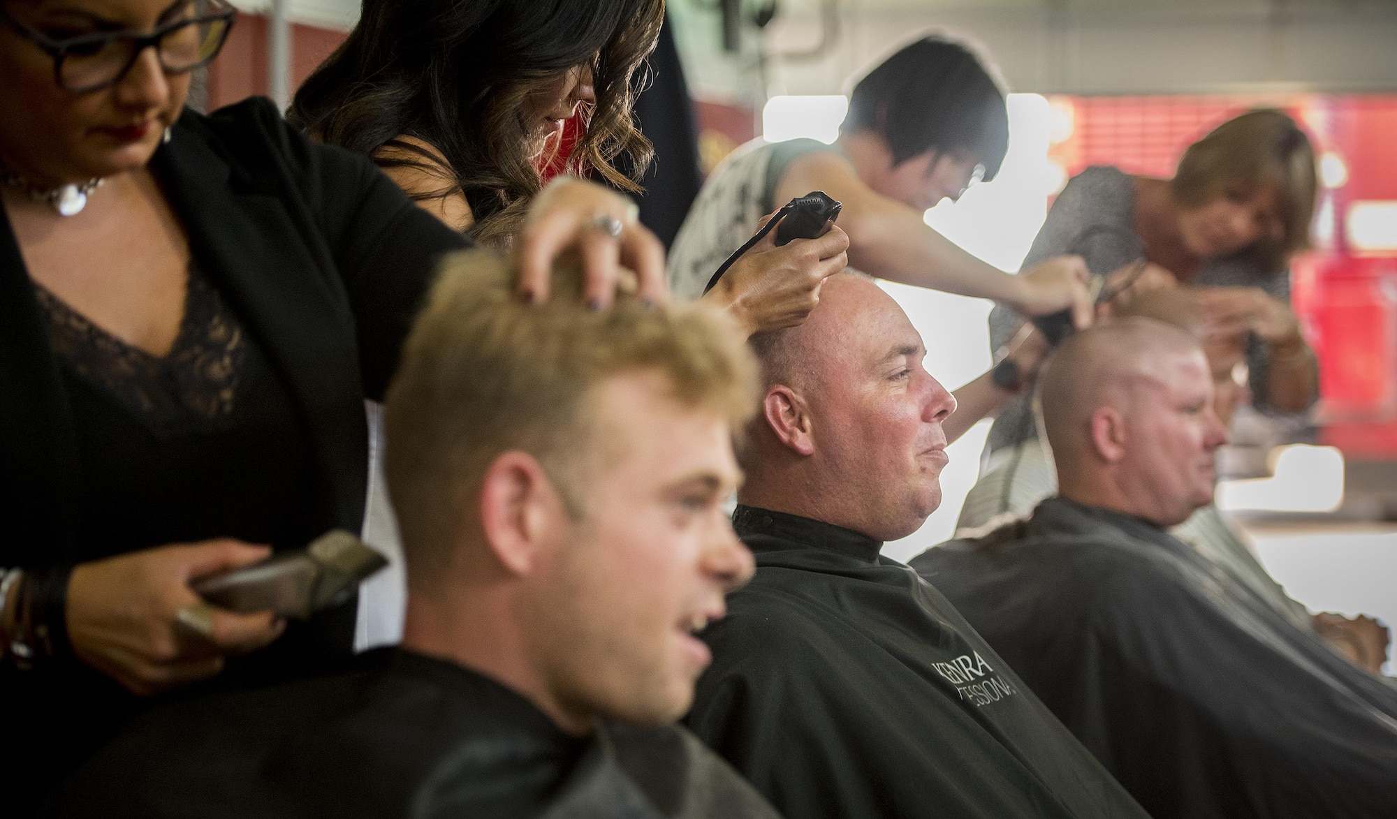 A group of firefighters receive a very close shave June 8 at Eglin Air Force Base, Fla.  Approximately 20 firefighters shaved their heads to raise awareness and funds for their crew mate, Terrance Curry, whose battled cancer continuously for 11 months.  (U.S. Air Force photo/Samuel King Jr.)