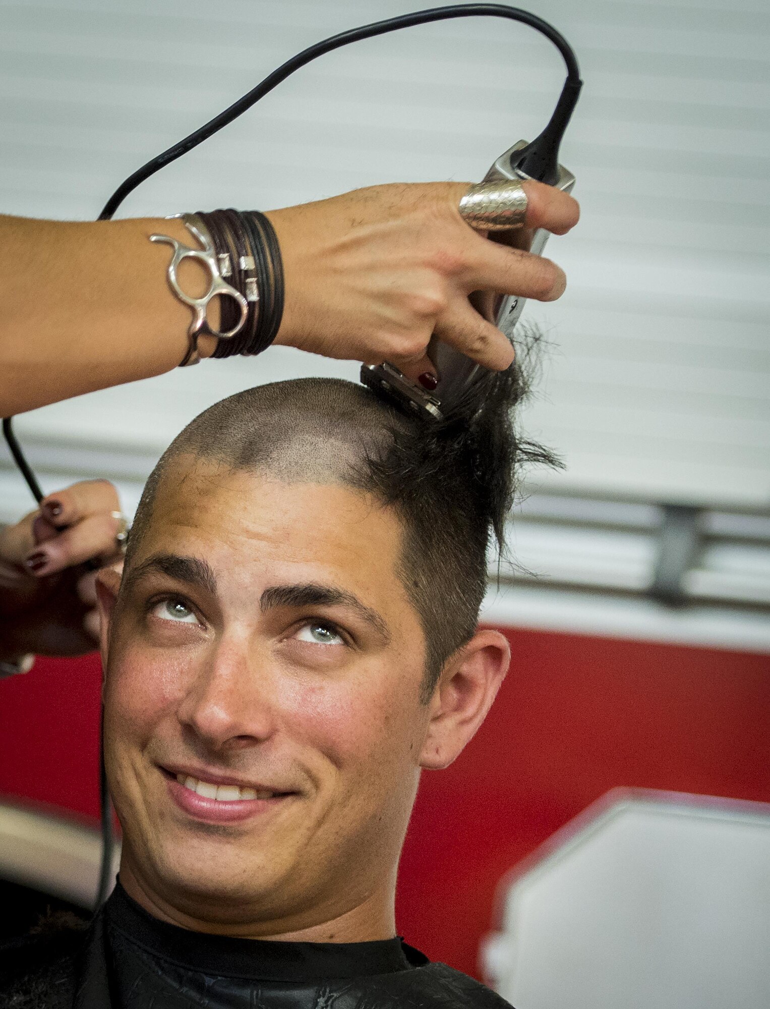 Senior Airman Cody Fulton, a 96th Test Wing firefighter, glances up as he loses his hair June 8 at Eglin Air Force Base, Fla.  Approximately 20 firefighters shaved their heads to raise awareness and funds for their crew mate, Terrance Curry, whose battled cancer continuously for 11 months.  (U.S. Air Force photo/Samuel King Jr.)