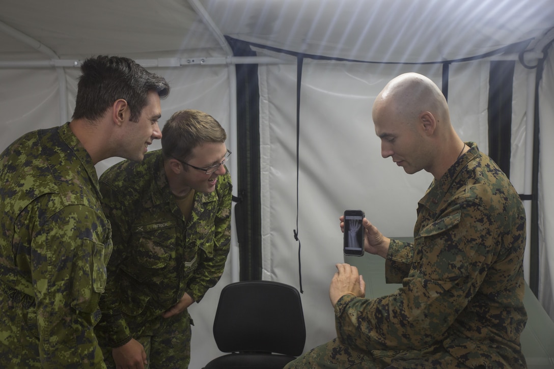 COLD LAKE, AB, CANADA – U.S. Navy Lt. Cmdr. Christian Basque, a navy doctor with Marine Wing Support Squadron 472, Marine Aircraft Group 49, 4th Marine Aircraft Wing, Marine Forces Reserve, shows pictures of X-rays from his civilian job as a sports medicine physician to Canadian medical technicians during exercise Maple Flag 50 at Canadian Forces Base Cold Lake, Alberta, June 2, 2017. Maple Flag is an annual multi-national training exercise hosted by the Royal Canadian Air Force with foreign nations training together to complete simulated combat missions. (U.S. Marine Corps photo by Lance Cpl. Niles Lee/Released)