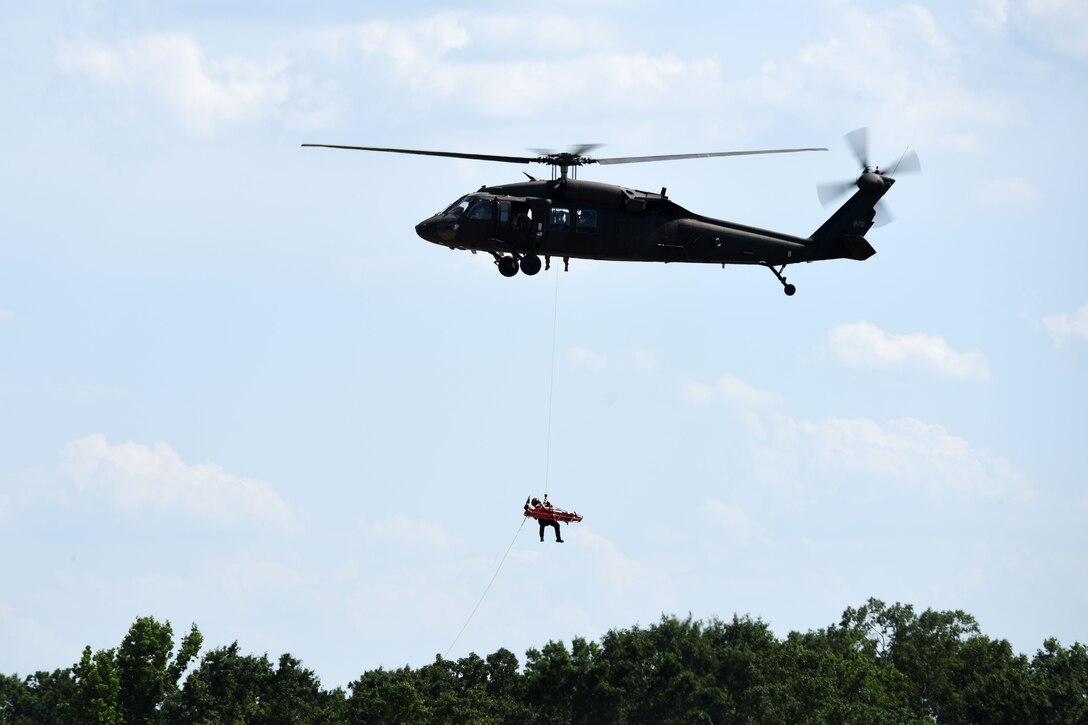 A UH-60L Black Hawk helicopter hovers while a mannequin on a stretcher is hoisted up onto a UH-60L Black Hawk helicopter during rescue training at the South Carolina Fire Academy campus, Columbia, S.C., June 2, 2017. Army National Guard photo by Staff Sgt. Roberto Di Giovine