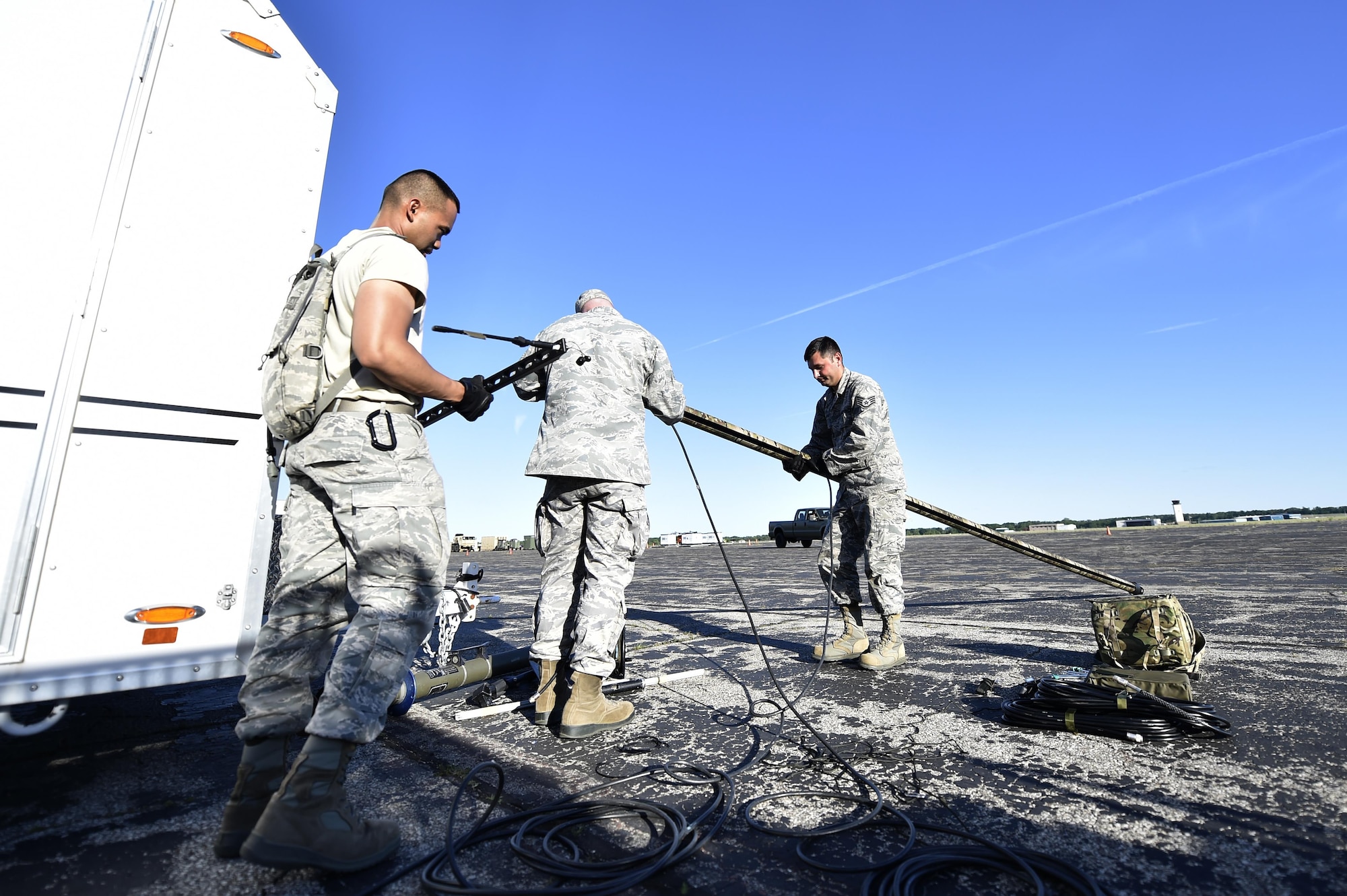 Senior Airman Zyrus Medina, Tech. Sgt. Joshua Pospisil, and Staff Sgt. Ronny Cox, 821st Contingency Response Support Squadron, set up the radio frequency transmission system during Exercise Turbo Distribution 17-02, June 7, 2017, at Battle Creek Air National Guard Base, Mich.  Turbo Distribution 17-2 is an U.S. Transportation Command exercise designed to assess the Joint Task Force-Port Opening's ability to deliver and distribute cargo during humanitarian and disaster relief operations. (U.S. Photo by Tech. Sgt. Liliana Moreno/Released)