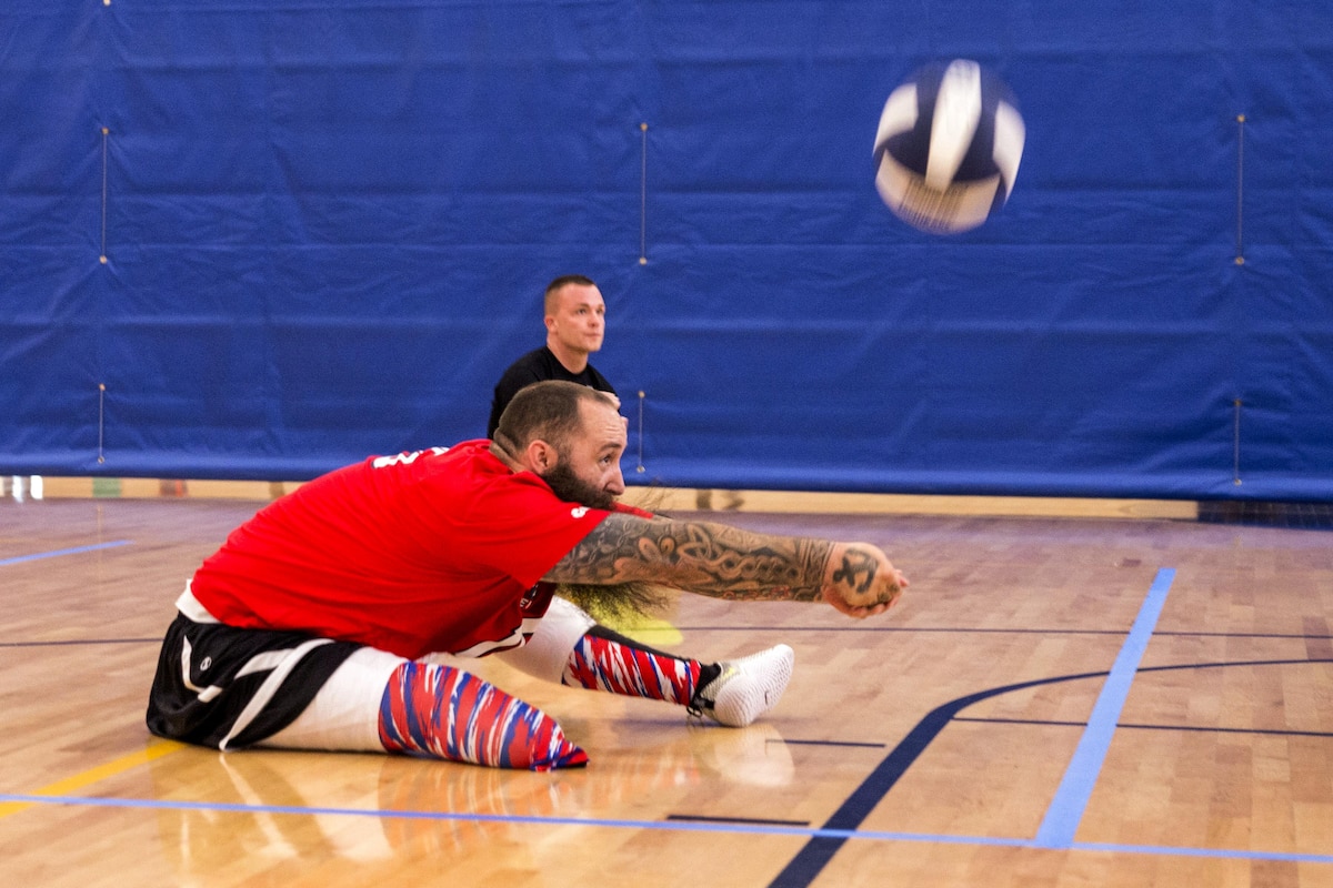 A retired sailor hits a ball during sitting volleyball drills.