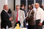 Tomas Beauchamp, Naval Surface Warfare Center (NSWC), Corona Division Corporate Operations Department head, left, chats with Jim Savage, JSL Technologies executive vice president, and Clifford Martin, ICI Services project manager, during Industry Day at Corona City Hall. The event, organized in cooperation with Riverside Community College District Procurement Assistance Center, included a keynote presentation by Emily Harman, Department of the Navy Office of Small Business Program director, a forecast of NSWC Corona future contracting/subcontracting opportunities as well as a series of meet-and-greet sessions for suppliers to network with technical department personnel.