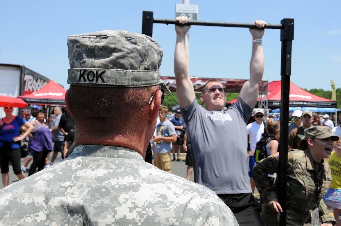 Maj. Gen. Troy D. Kok, commanding general of the U.S. Army Reserve’s 99th Regional Support Command, headquartered at Joint Base McGuire-Dix-Lakehusrt, New Jersey, watches June 10 as Spc. Alex High, part of the honor guard at Ft. Meyer, Virginia, completes pull-ups at the GoArmy experience during “Army Day At The Races” at Old Bridge Township Raceway Park in Englishtown, New Jersey.  Kok was at the event to help celebrate the Army’s 242nd birthday during the National Hot Rod Association’s Summernationals.