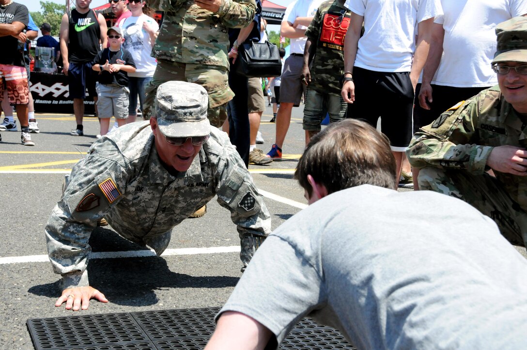 Maj. Gen. Troy D. Kok, commanding general of the U.S. Army Reserve’s 99th Regional Support Command, headquartered at Joint Base McGuire-Dix-Lakehusrt, New Jersey, completes push-ups with a teenage boy June 10 at the GoArmy experience during “Army Day At The Races” at Old Bridge Township Raceway Park in Englishtown, New Jersey.  Kok was at the event to help celebrate the Army’s 242nd birthday during the National Hot Rod Association’s Summernationals.