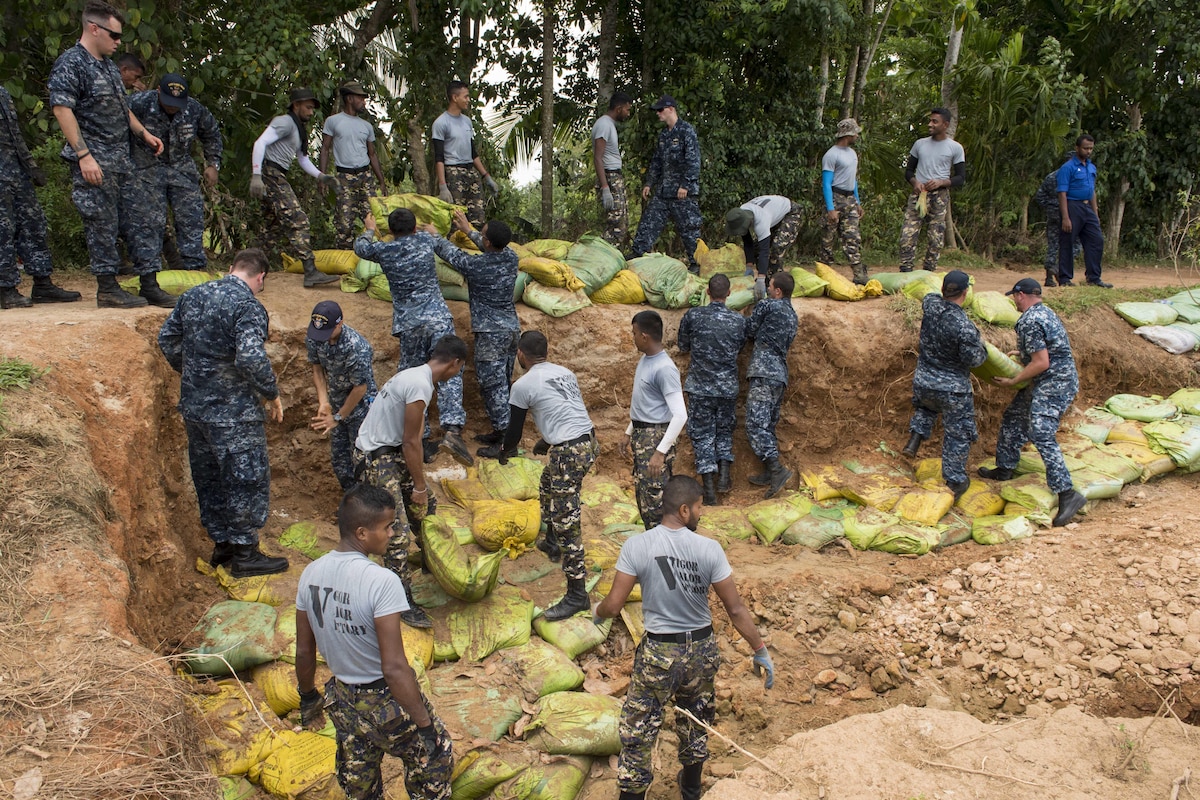 Sailors work with Sri Lankan marines to repair a levee.