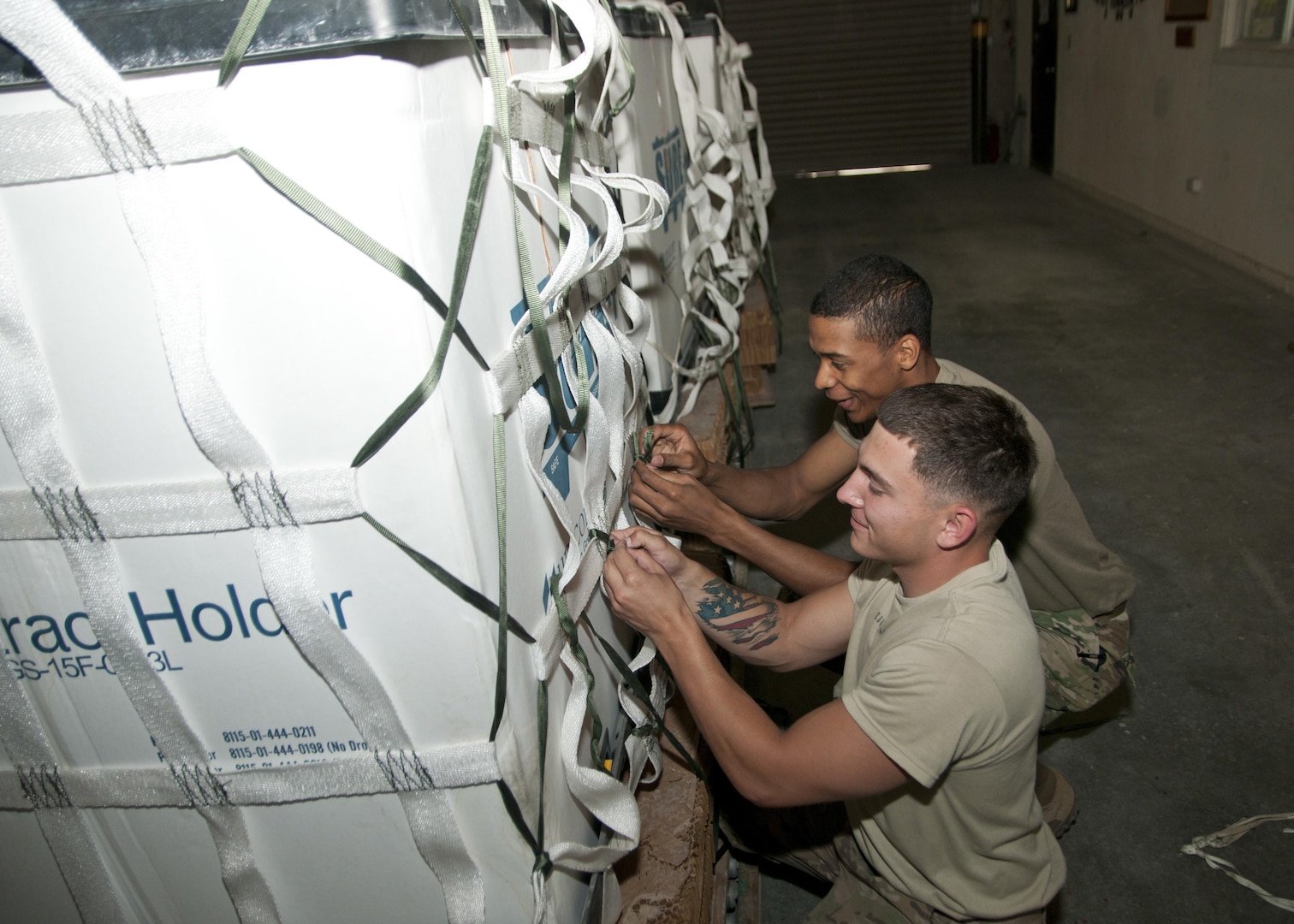 Pfc. Noah Buckhouse and Spc. John Caulder of the 824th Quartermaster Company, secure a container with cargo netting for aerial delivery at Al Udeid Air Base, Qatar on April 25, 2017. Aerial delivery operations are essential for getting supplies to troops in the Middle East when conventional means of transportation are not feasible. (U.S. Army photo by Sgt. Jeremy Bratt)