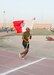 Master Sgt. Edgar Ponce, of the 369th Sustainment Brigade, carries the brigade colors over the finish line in the inaugural Harlem Hellfighter 5K run, held at Camp Arifjan, Kuwait on June 2, 2017. The event was held to celebrate the 104th anniversary of the formation of the historic New York National Guard unit. The unit was given their historic nickname “Hellfighters” by their German opponents in WWI for their remarkable prowess on the battlefield. (U.S. Army photo by Sgt. Jeremy Bratt)
