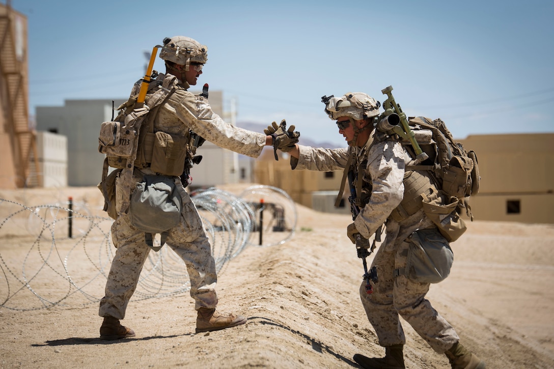MARINE CORPS AIR GROUND COMBAT CENTER TWENTYNINE PALMS, California – Cpl. Cameron Halkovich (left), a combat engineer attached to 2nd Battalion, 7th Marine Regiment, assists another Marine up a steep hill during an urban assault at Range 200 aboard Marine Corps Air Ground Combat Center Twentynine Palms, California, May 16, 2017. The Urban Warfare Package, part of Integrated Training Exercise 3-17, is a platoon-level to battalion-size evolution where Marines practiced urban patrolling, leading up to a Marine Air Ground Task Force assault on an enemy held town. ITX is a training evolution conducted five times a year to enhance the lethality and co-operability between the four elements of a Marine Air Ground Task Force. (U.S. Marine Corps photo by Cpl. Jesus Sepulveda Torres)