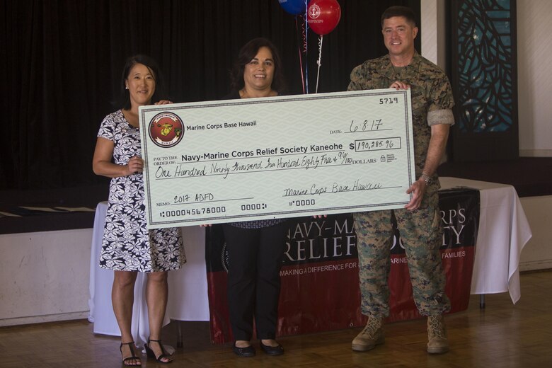 Judy Otero (left), a relief service assistant with the Navy-Marine Corps Relief Society, Cheryl Milca (middle), the director of the Navy-Marine Corps Relief Society, and Col. Sean Killeen (right), base commanding officer, MCB Hawaii, present a check representing the amount of money donated by service members at the Officers’ Club ballroom aboard MCB Hawaii on June 8, 2017. The Navy-Marine Corps Relief Society hosted this ceremony to recognize the units that donated over $190,000 to the Active Duty Fund Drive. (U.S. Marine Corps photo by Lance Cpl. Isabelo Tabanguil)