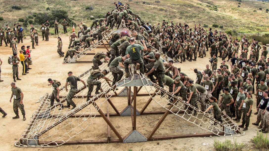 Marines and sailors conduct the cargo net climb while participating in the 2017 Marine Corps Mud Run at Camp Pendleton, Calif., June 9, 2017. The event included mud pits, an ammunition can run and other challenges. Marine Corps photo by Sgt. Hector de Jesus