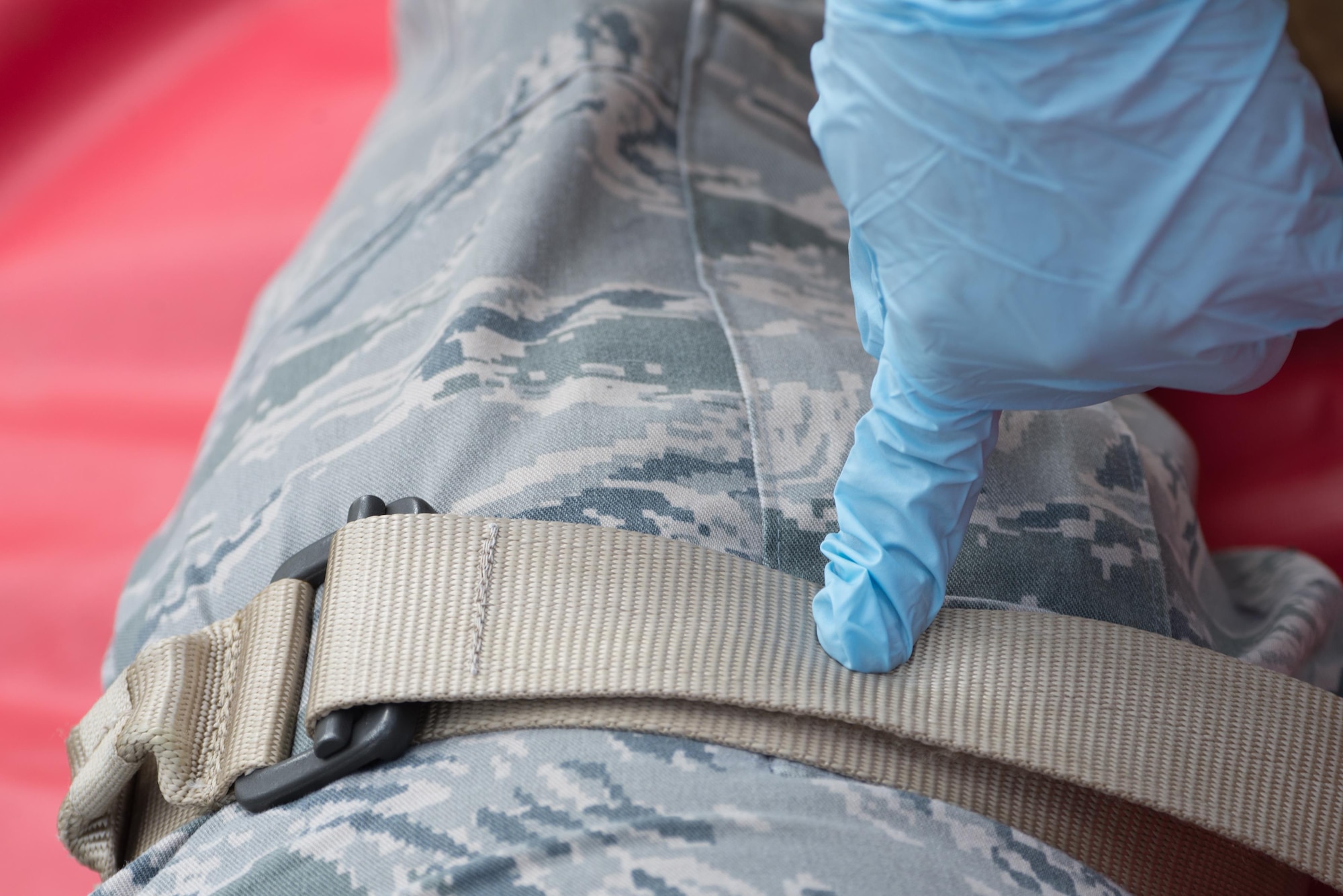 An emergency responder uses a belt to apply pressure to a simulated leg injury during an emergency management exercise May 11, 2017, at Andersen Air Force Base, Guam. The 36th Wing exercises regularly to ensure base personnel are trained and ready to respond quickly and accurately in the event of a crisis. (U.S. Air Force photo by Airman 1st Class Jacob Skovo)