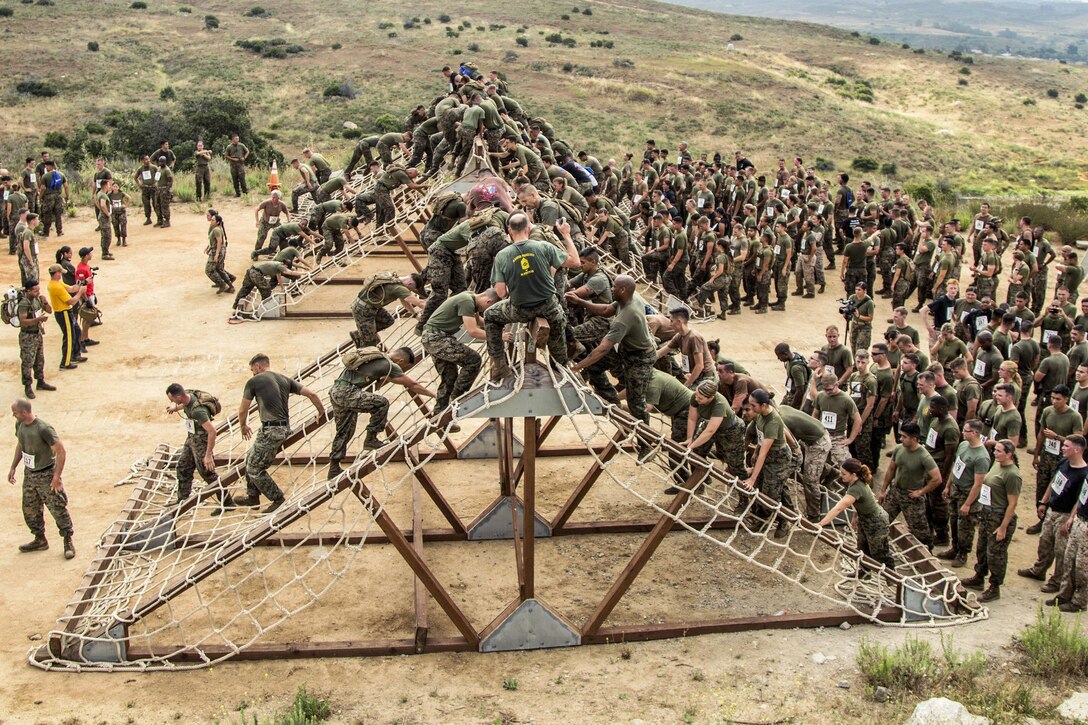 Marines and sailors conduct the cargo net climb while participating in the 2017 Marine Corps Mud Run at Camp Pendleton, Calif., June 9, 2017. The event included mud pits, an ammunition can run and other challenges. Marine Corps photo by Sgt. Hector de Jesus