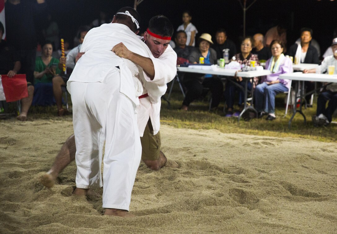 Lance Cpl. Giovanni L. Ramires (right center) leg sweeps his opponent, June 10, 2017, during the annual Henoko Okinawa-Style Sumo Tournament at Mae-No-Hama Field in Henoko, Okinawa, Japan. During a bout, competitors try to earn points by making their opponent fall into the “dohyo,” or sandy pit, without striking or letting go of each other’s belts. The first to gain two points is the victor. Okinawa-style sumo wrestling, also known as kakuriki, is a combination of western wrestling and traditional Japanese sumo and judo, according to Fumio Iha, Camp Schwab’s community relations specialist. Ramires is a native of Johnstown, Pennsylvania, and an intelligence specialist with 3rd Intelligence Battalion, III Marine Expeditionary Force Headquarters Group. (U.S. Marine Corps photo by Lance Cpl. Andy Martinez)