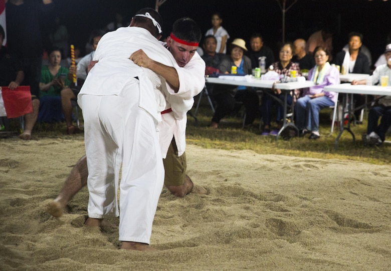 Lance Cpl. Giovanni L. Ramires (right center) leg sweeps his opponent, June 10, 2017, during the annual Henoko Okinawa-Style Sumo Tournament at Mae-No-Hama Field in Henoko, Okinawa, Japan. During a bout, competitors try to earn points by making their opponent fall into the “dohyo,” or sandy pit, without striking or letting go of each other’s belts. The first to gain two points is the victor. Okinawa-style sumo wrestling, also known as kakuriki, is a combination of western wrestling and traditional Japanese sumo and judo, according to Fumio Iha, Camp Schwab’s community relations specialist. Ramires is a native of Johnstown, Pennsylvania, and an intelligence specialist with 3rd Intelligence Battalion, III Marine Expeditionary Force Headquarters Group. (U.S. Marine Corps photo by Lance Cpl. Andy Martinez)
