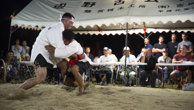 Lt. Col. James Dorlon (left) holds his ground, June 10, 2017, during the annual Henoko Okinawa-Style Sumo Tournament, at Mae-No-Hama Field, in Henoko, Okinawa, Japan. During a bout, competitors try to earn points by making their opponent fall into the dohyo, or sandy pit, without striking each other or letting go of each other’s belts. The first to gain two points is the victor. Dorlon is a native of Beaverton, Oregon, and the commanding officer of Jungle Warfare Training Center, 3rd Marine Division, III Marine Expeditionary Force. (U.S. Marine Corps photo by Lance Cpl. Andy Martinez)