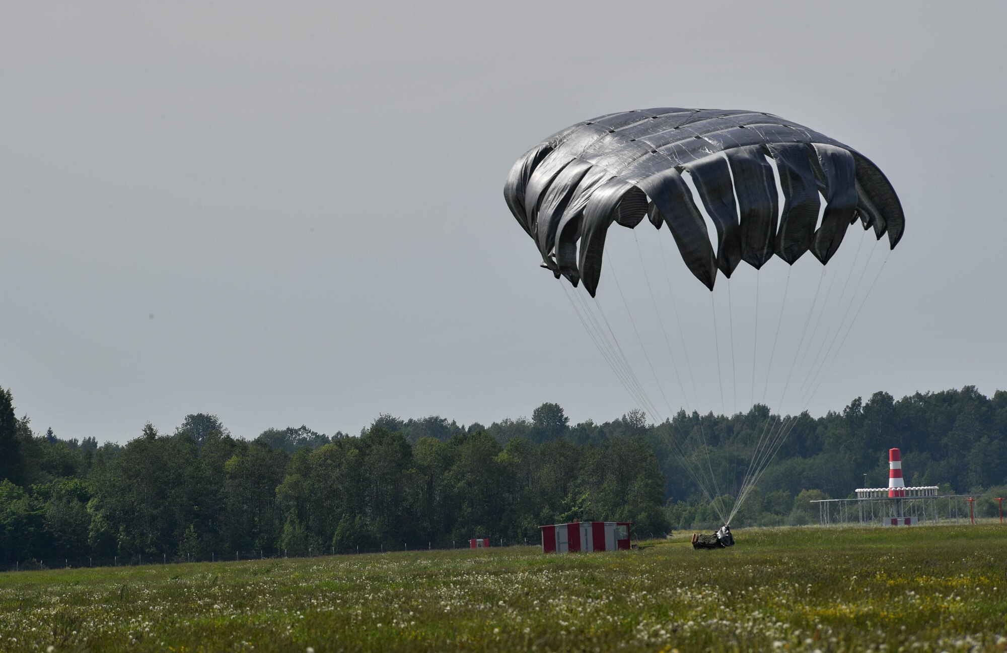 A pallet of equipment lands on the ground after being dropped out of a U.S. Air Force C-130J Super Hercules during exercise Saber Strike 17 on Lielvārde Air Base, Latvia, June 7, 2017. The 435th Contingency Response Group from the 435th Air Ground Operations Wing at Ramstein Air Base, Germany, dropped the bundle to practice assessing an area for aircraft landings. Saber Strike 17 continues to increase participating nations’ capacity to conduct a full spectrum of military operations. (U.S. Air Force photo by Senior Airman Tryphena Mayhugh)