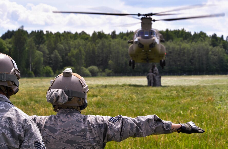 U.S. Air Force Staff Sgt. Edgar Cerrillo, 435th Security Forces Squadron Ground Combat Readiness Training Center instructor, gives hand signals to a U.S. Army CH-47 Chinook for the 435th Contingency Response Group’s sling load operation during exercise Saber Strike 17 at Lielvarde Air Base, Latvia, June 10, 2017. 435th CRG Airmen connected a bundle to the Chinook to practice properly rigging cargo for a sling load operation. Saber Strike 17 promotes regional stability and security, while strengthening partner capabilities and fostering trust. (U.S Air Force photo by Senior Airman Tryphena Mayhugh)