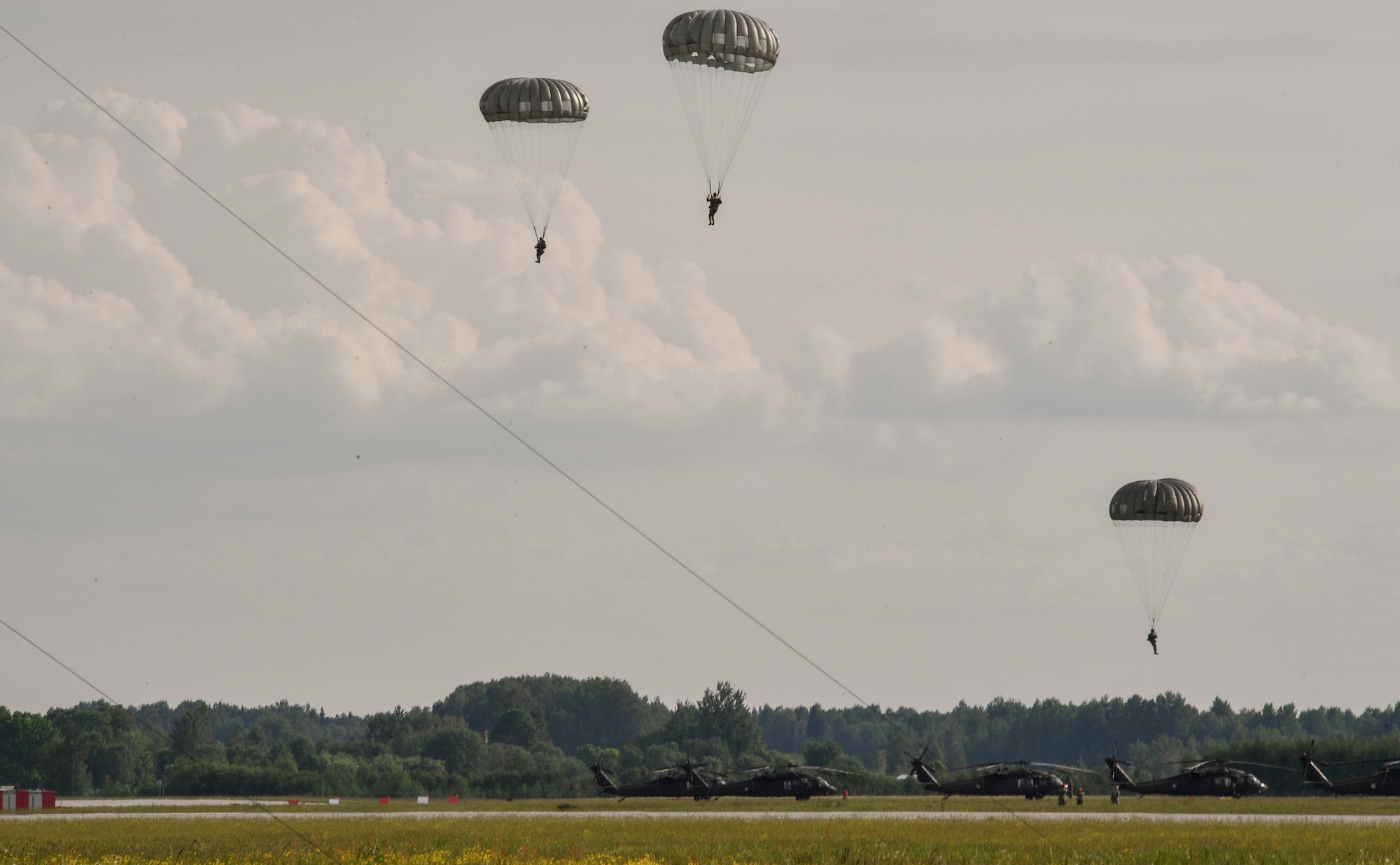 U.S. Air Force Airmen assigned to the 435th Contingency Response Group float to the ground after jumping from a U.S. Army CH-47 Chinook for the 435th Contingency Response Group’s sling load during exercise Saber Strike 17 at Lielvarde Air Base, Latvia, June 10, 2017. The 435th CRG sends paratroopers to austere locations to determine if an area can be safely used as an airfield. Saber Strike 17 highlights the inherent flexibility of ground and air forces to rapidly respond to crises allowing for the right presence where it is needed, when it is needed. (U.S Air Force photo by Senior Airman Tryphena Mayhugh)