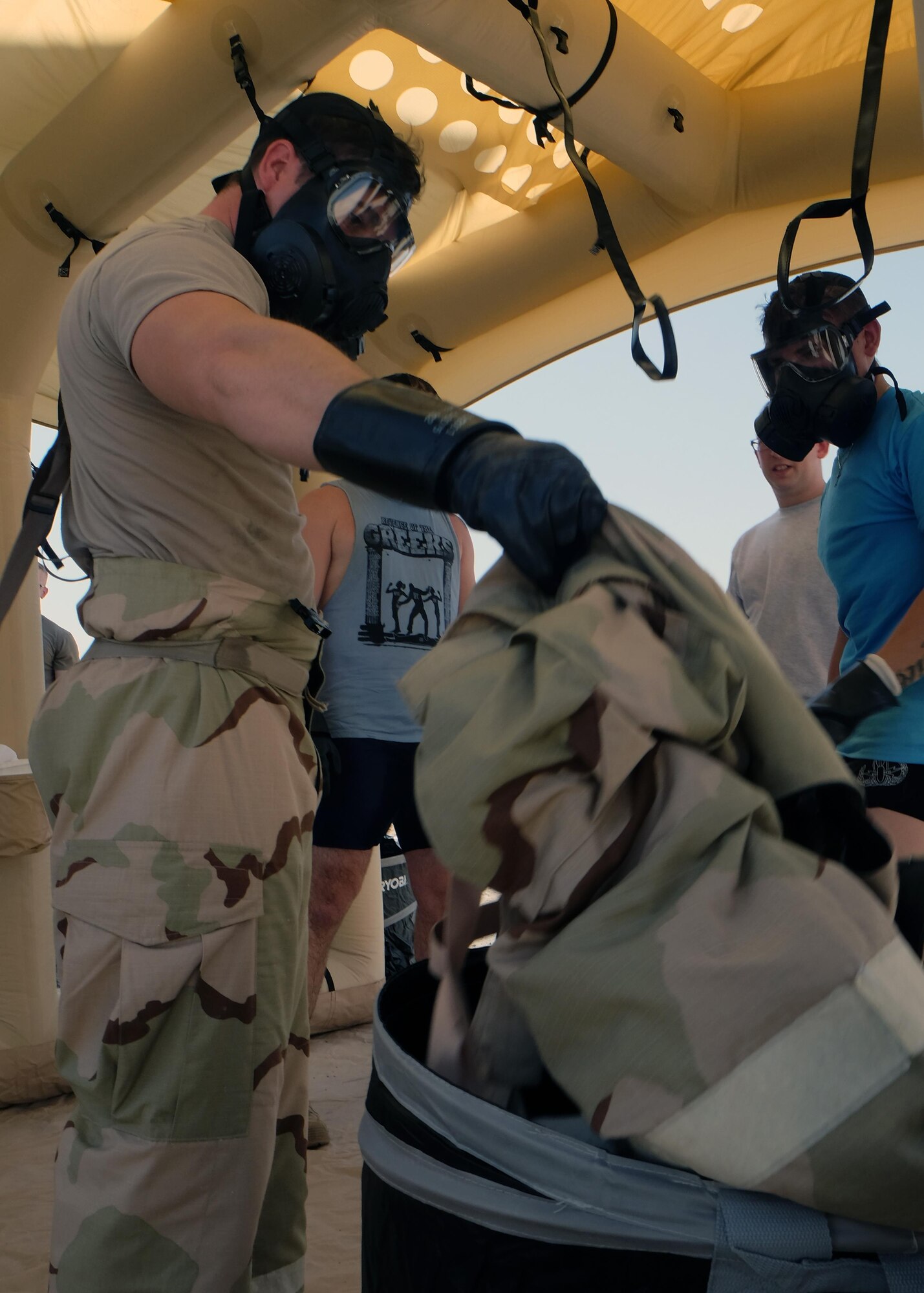 Airmen with the 380th Expeditionary Civil Engineer Squadron discard 'contaminated' equipment during Contamination Control Area training in a Lightweight Inflatable Decontamination System June 8, 2017, at an undisclosed location in southwest Asia. The purpose of the CCA was to train Airmen and Soldiers on how to properly remove contaminated individual protective equipment after a chemical or biological attack. (U.S. Air Force photo by Senior Airman Preston Webb)