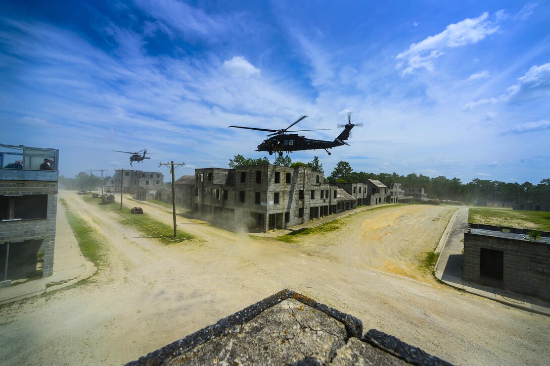 UH-60 Black Hawk helicopters, part of the 160th Special Operations Aviation Regiment, hover while Army Rangers prepare to fast rope onto buildings during an exercise hosted by U.S. Army Special Operations Command, Fort Bragg, N.C., June 6, 2017. Special Operations Command photo by Michael Bottoms