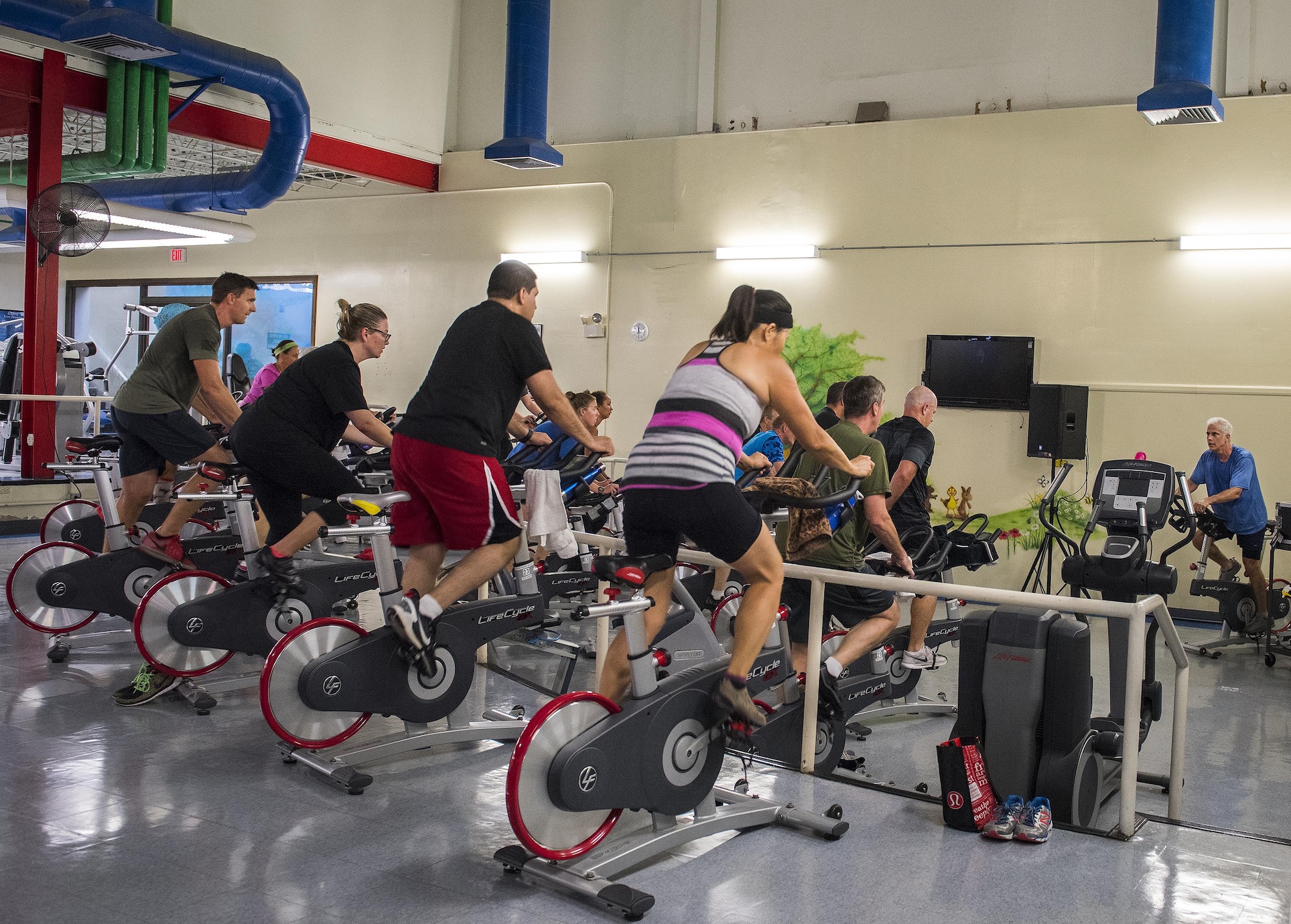 Spin class attendees utilize bikes, relocated from the main fitness center, during a lunch-time class at the Premier Fitness Laboratory, previously known as the Fitness Annex. The Lab, closed for general recreation, is open exclusively for group exercise, fitness improvement training, spin classes, and personal training. (U.S. Air Force photo/Kristin Stewart)