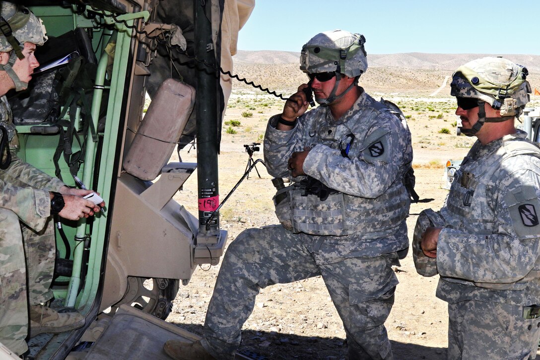 Army Spc. Joshua Lomax, a member of the Mississippi National Guard, center, and 1st Lt. Joshua Carmichael coordinate indirect fire missions during a live-fire exercise at the National Training Center, Fort Irwin, Calif., June 9, 2017. Lomax and Carmichael are assigned to the 155th Armored Brigade Combat Team, 2nd Battalion, 198th Armored Regiment. Mississippi National Guard photo by Staff Sgt. Shane Hamann 
