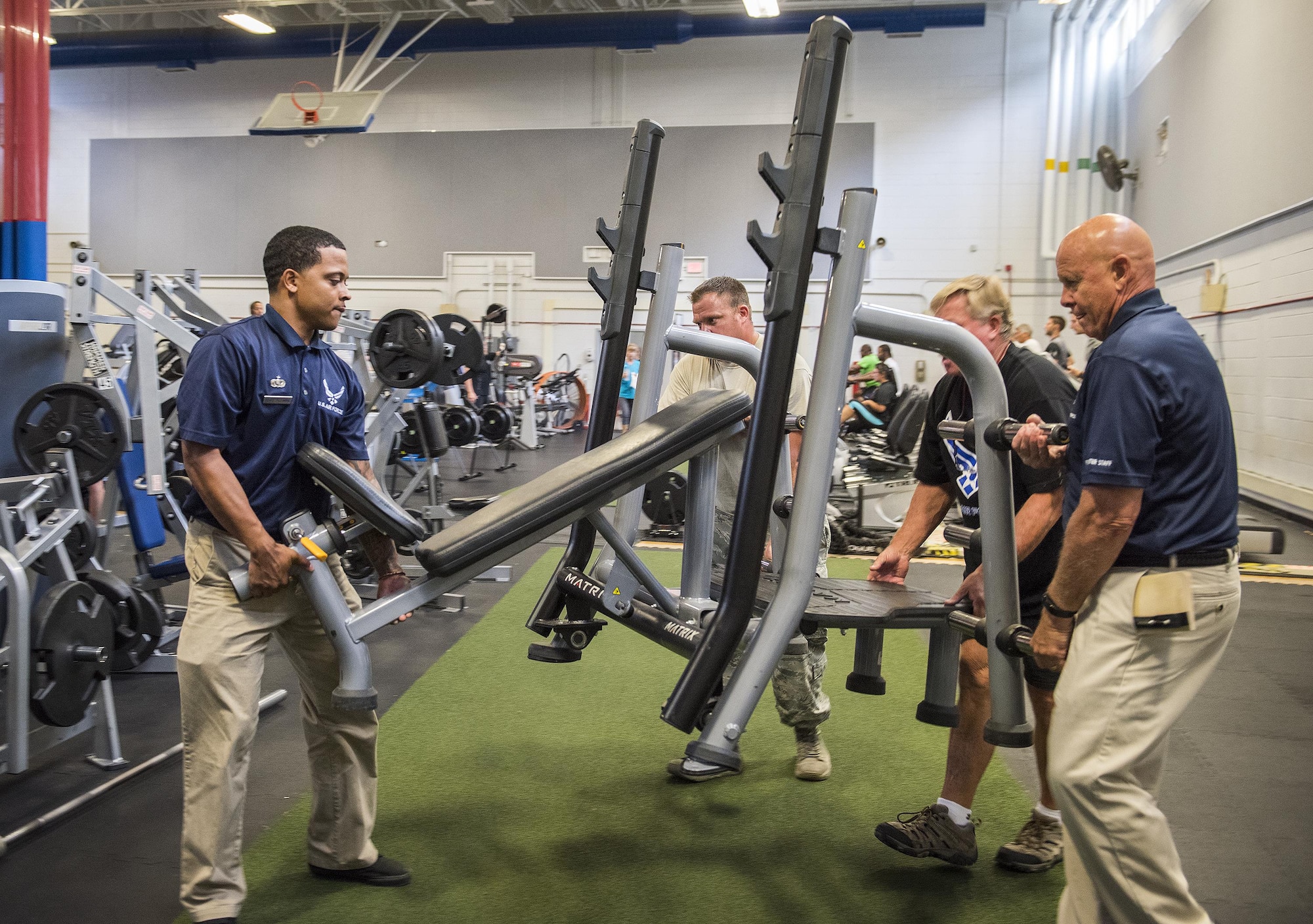 Fitness center staff rearrange equipment in the free weight room of the main fitness center. By relocating spin bikes to the Premier Fitness Laboratory, previously known as the Fitness Annex, it created additional work out space for base personnel. The Lab is now open exclusively for group exercise, fitness improvement training, spin classes, and personal training. (U.S. Air Force photo/Kristin Stewart)