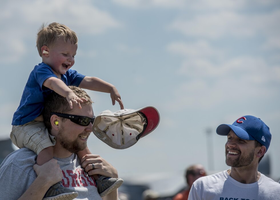 A boy throws off the hat of his father during the Scott Air Force Base Air Show, Scott Air Force Base, Ill., June 11, 2017. The base hosted the air show and open house to celebrate the 100th year of Scott AFB.  Over 50 aircraft, ranging from WWI’s Curtiss JN-4 Jenny to the currently utilized KC-135 Stratotanker, came to Scott, the fourth oldest Air Force base. Demonstrations included the Black Daggers, “Tora, Tora, Tora,” and the USAF Thunderbirds. Opened in 1917 and previously named Scott Field, the base has seen its mission evolve and expand to encompass a multitude of priorities, including aeromedical evacuation and communications.  Today, Scott is home to 31 mission partners and provides around-the-clock logistics support and rapid global mobility, carried out primarily by U.S. Transportation Command and Air Mobility Command.