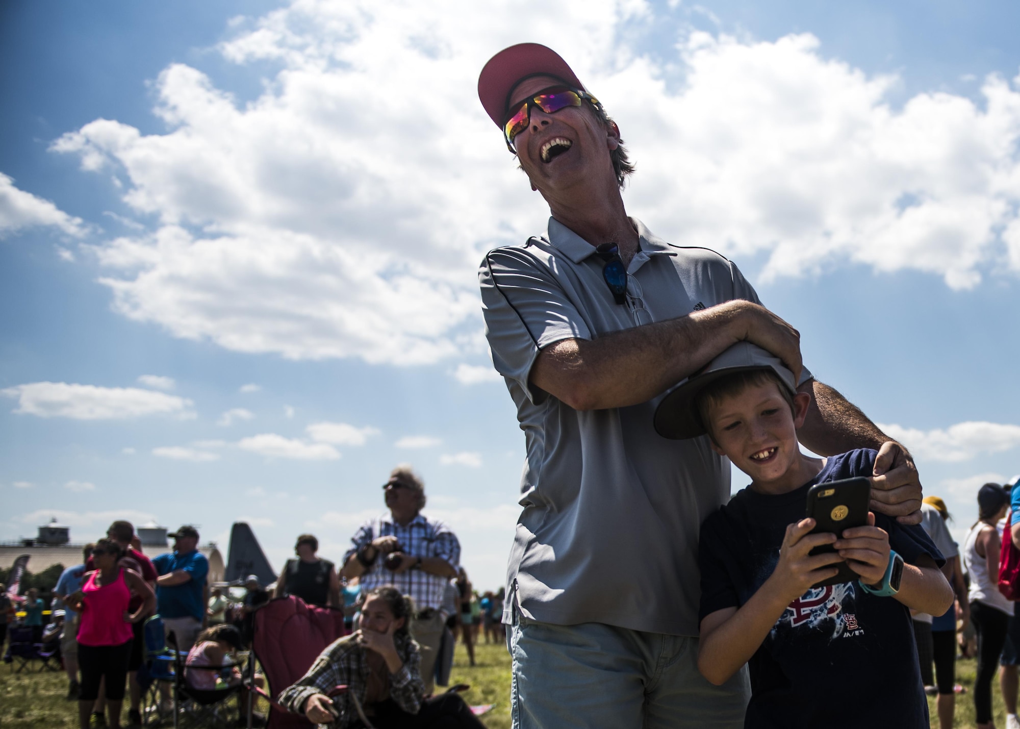 A father embraces his son in laughter after the Thunderbirds's roar startled him during the Scott Air Force Base Air Show, Scott Air Force Base, Ill., June 11, 2017. The base hosted the air show and open house to celebrate the 100th year of Scott AFB.  Over 50 aircraft, ranging from WWI’s Curtiss JN-4 Jenny to the currently utilized KC-135 Stratotanker, came to Scott, the fourth oldest Air Force base. Demonstrations included the Black Daggers, “Tora, Tora, Tora,” and the USAF Thunderbirds. Opened in 1917 and previously named Scott Field, the base has seen its mission evolve and expand to encompass a multitude of priorities, including aeromedical evacuation and communications.  Today, Scott is home to 31 mission partners and provides around-the-clock logistics support and rapid global mobility, carried out primarily by U.S. Transportation Command and Air Mobility Command.