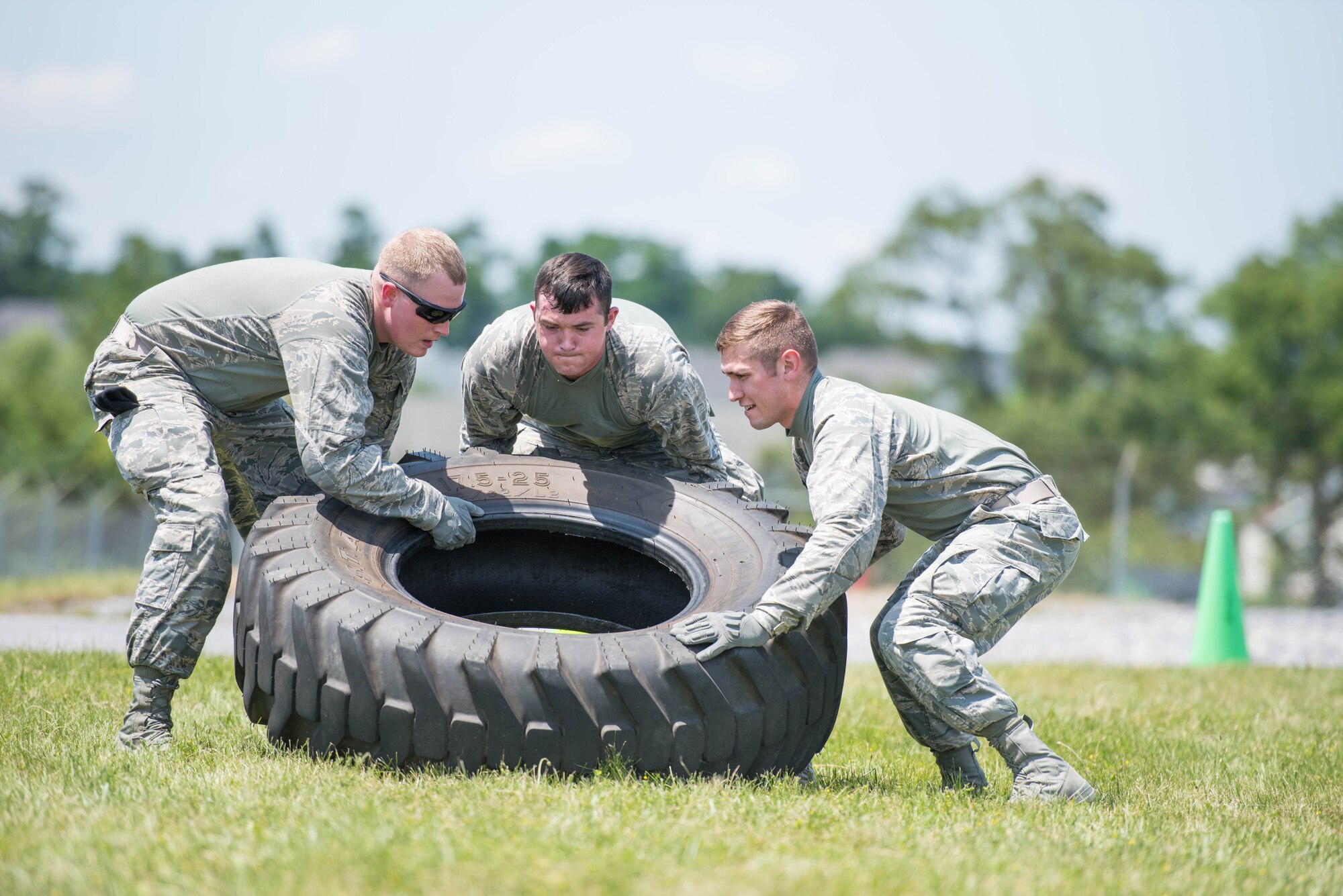 Members of security forces at the 167th Airlift Wing in Martinsburg, W.Va., Airman 1st Class Jamie Bryner (left), Airman 1st Class Jalen Newcome (middle), and Airman 1st Class Cody Kunkleman (right), lift a tire during an expeditionary fitness challenge with both strength and stamina events, June 10, 2017. The course consisted of seven stations, where teams of five, moved as a unit from location to location and were scored by station and overall time. (U.S. Air National Guard photo by Staff Sgt. Jodie Witmer)