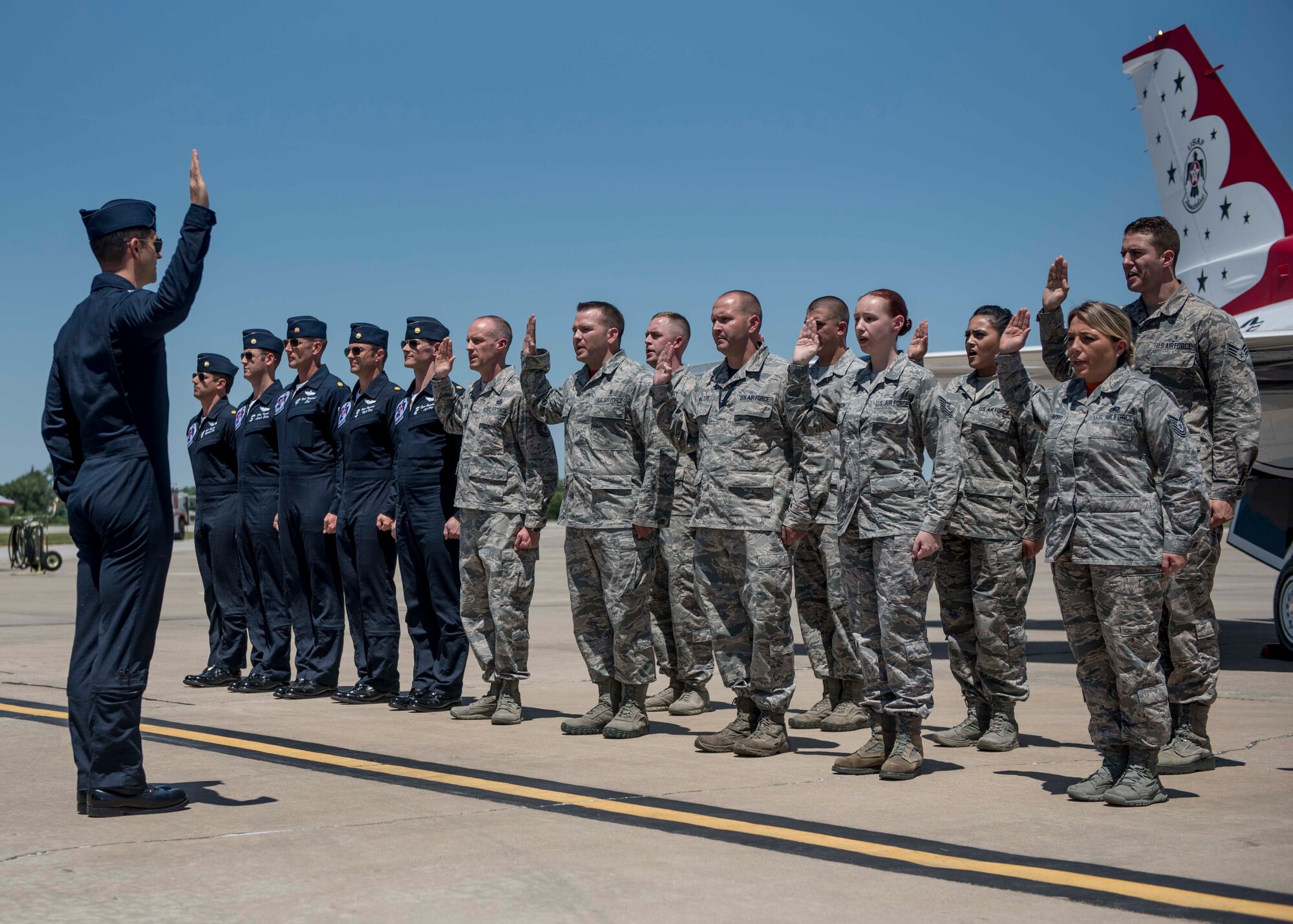 A group of Airmen reenlist into the Air Force with the Thunderbirds during the Scott Air Force Base Air Show, Scott Air Force Base, Ill., June 11, 2017. The base hosted the air show and open house to celebrate the 100th year of Scott AFB.  Over 50 aircraft, ranging from WWI’s Curtiss JN-4 Jenny to the currently utilized KC-135 Stratotanker, came to Scott, the fourth oldest Air Force base. Demonstrations included the Black Daggers, “Tora, Tora, Tora,” and the USAF Thunderbirds. Opened in 1917 and previously named Scott Field, the base has seen its mission evolve and expand to encompass a multitude of priorities, including aeromedical evacuation and communications.  Today, Scott is home to 31 mission partners and provides around-the-clock logistics support and rapid global mobility, carried out primarily by U.S. Transportation Command and Air Mobility Command.