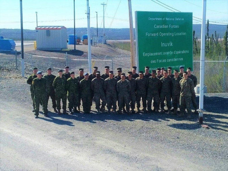 Staff at Canadian Armed Forces Forward Operating Location Inuvik pose for a picture with Marines from with Engineer Company, Detachment Bravo, Marine Wing Support Squadron 473, 4th Marine Aircraft Wing, Marine Forces Reserve at the entrance to FOL Inuvik, May 31, 2017. The Marines completed engineering projects at FOL Inuvik to increase force protection measures at FOL Inuvik during their two-week annual training period, May 26 to June 9, 2017.