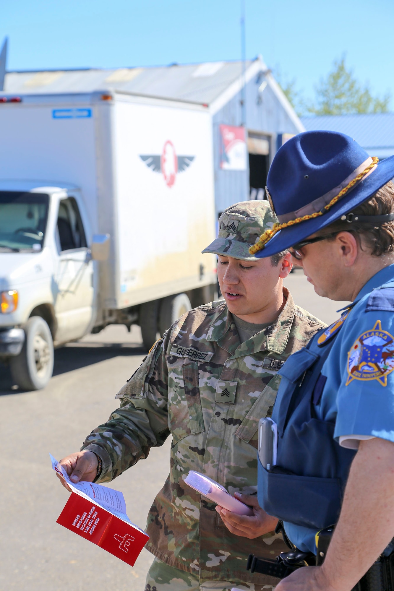 Alaska National Guard Sgt. Elijah Gutierrez, a civil operator with the Counter Drug Support Program, discusses the procedures for using the Narcan kit with Alaska State Trooper James Lester at the Edward G. Pitka Sr. Airport in Galena, Alaska, May 31, 2017. Twelve Guardsmen from the CDSP traveled to the Yukon-Koyukuk Region hub to deliver the kits that block the effects of opioids and reverses an overdose, and to provide drug and alcohol education and prevention materials to local residents. (U.S. Army National Guard photo by Staff Sgt. Balinda O’Neal Dresel) 