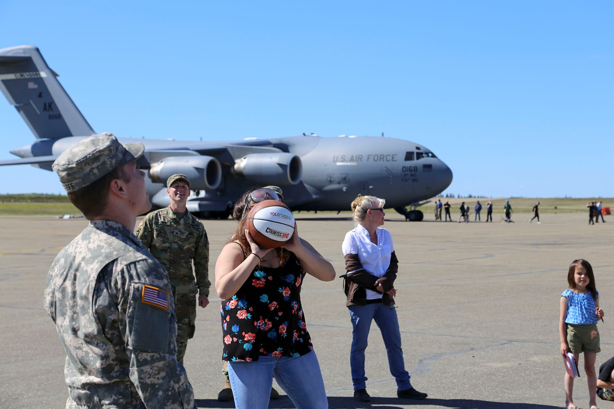 Alaska National Guard Warrant Officer Josiah Streff, left, and Sgt. Austin Makowski, both with the Counterdrug Support Program, watch as a local resident tries to shoot a basketball into a hoop while wearing vision impairment goggles at the Edward G. Pitka Sr. Airport in Galena, Alaska, May 31, 2017. The CDSP presented the goggles, a tool used to demonstrate alcohol or drug impairment, and provided drug and alcohol education and prevention materials to local residents during a recent civil operations mission in the Yukon-Koyukuk Region. (U.S. Army National Guard photo by Staff Sgt. Balinda O’Neal Dresel)