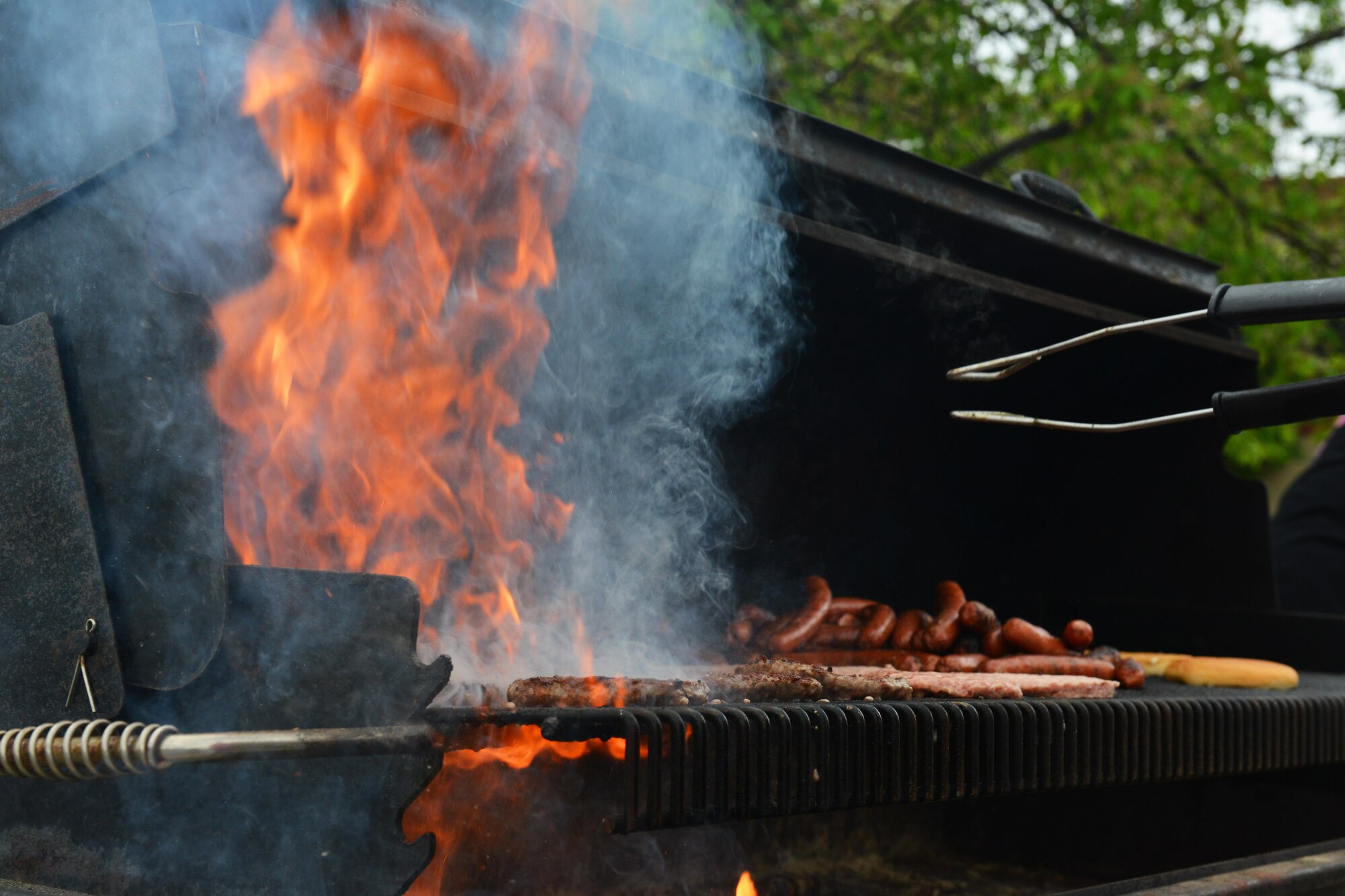 Burgers and hotdogs, courtesy of Arctic Oasis cook on a grill at the Joint Base Elmendorf-Richardson car show, June 10, 2017. The food was free to everyone in attendance.