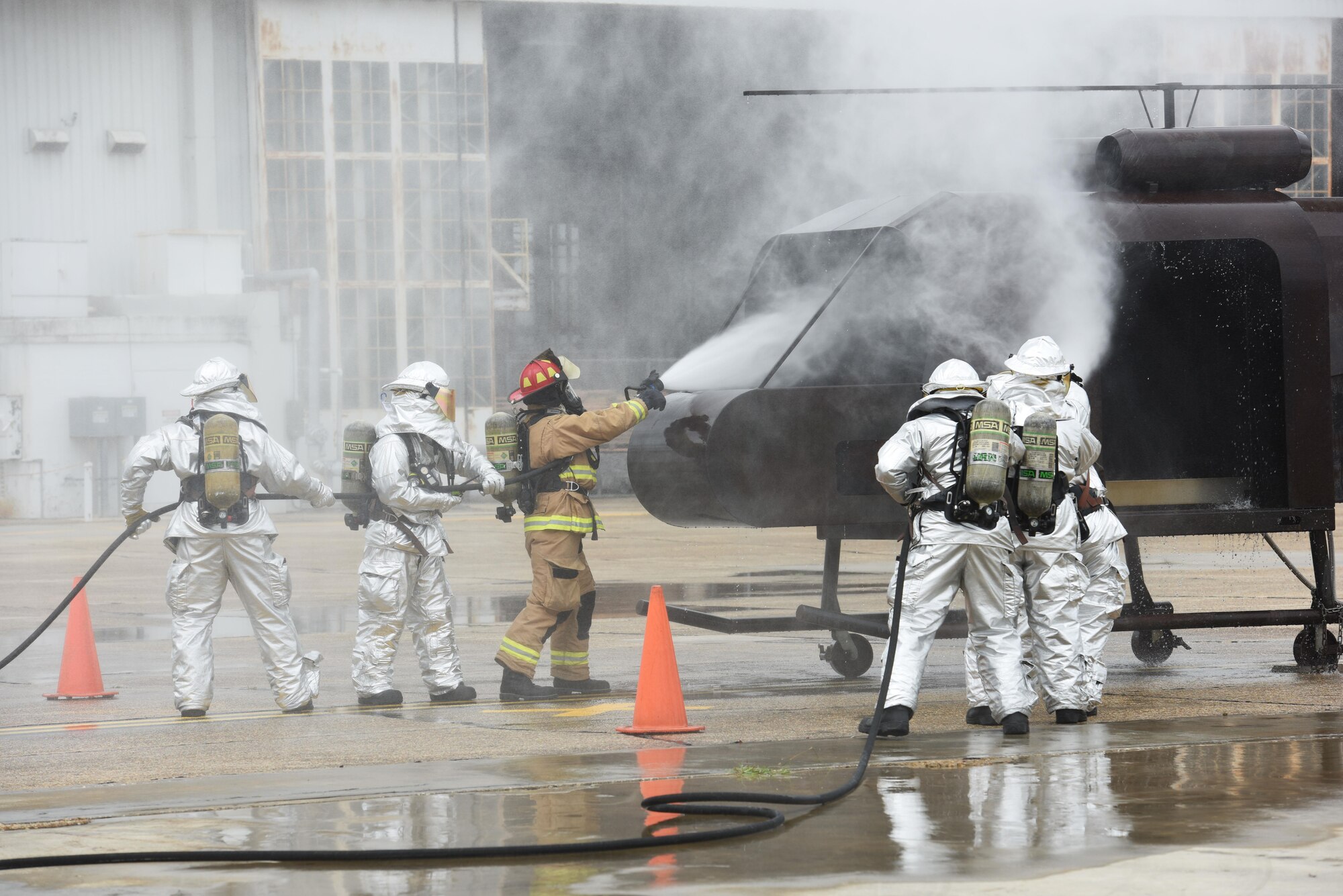 Firefighters from Keesler and the Combat Readiness Training Center, Gulfport, Miss., use hand-held hoses on a firefighter training aid during a live fire exercise on the flightline June 6, 2017, on Keesler Air Force Base, Miss. The Keesler Fire Department, the Gulfport CRTC Fire Department and the Stennis Space Center Fire Department are all required to practice Aircraft Rescue and Fire Fighting procedures to meet a semi-annual training requirement. (U.S. Air Force photo by Kemberly Groue)