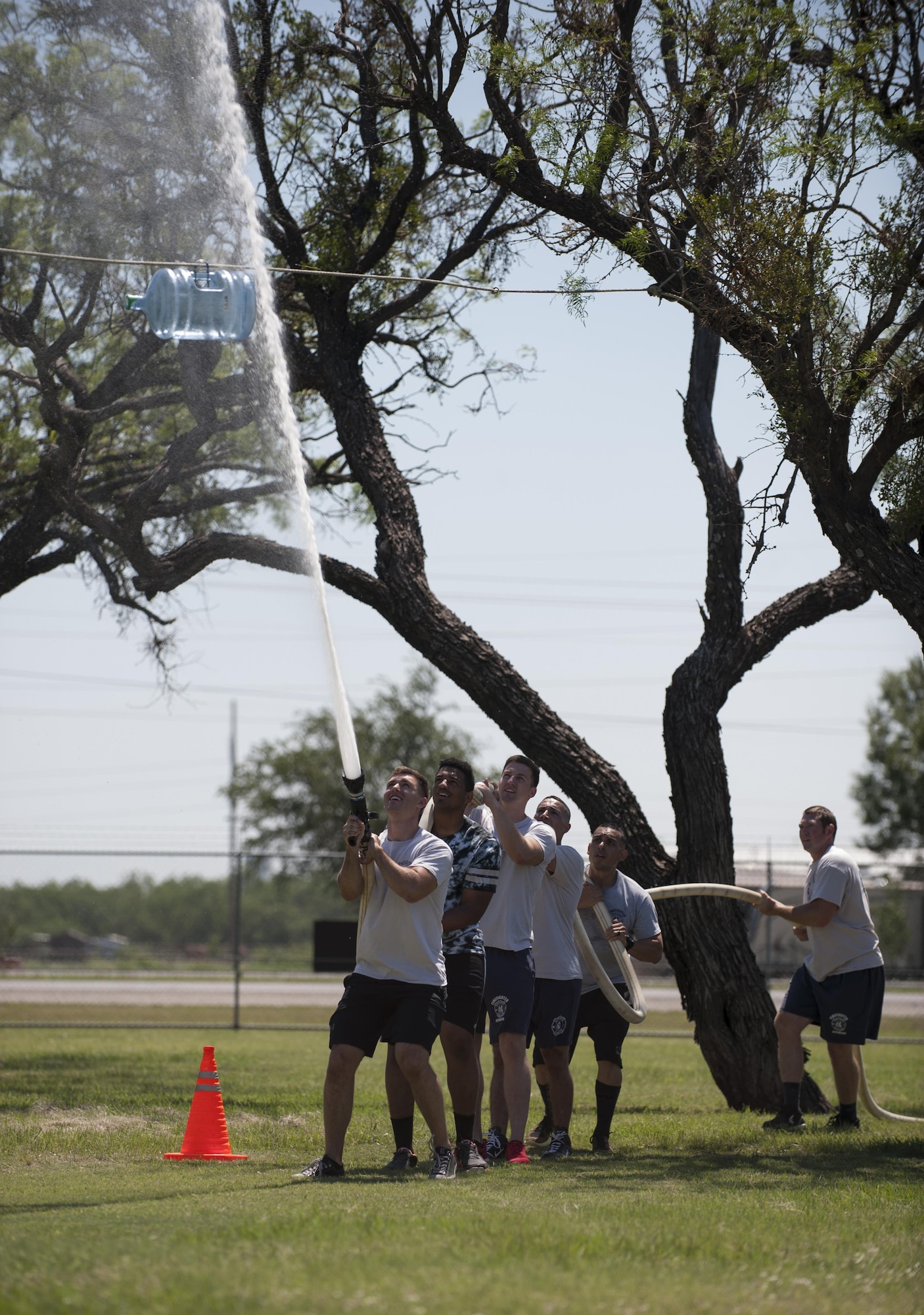 The 7th Civil Engineer Squadron Fire Department team uses a hose to push a water jug to the finish line during Battle of the Badges at Dyess Air Force Base, Texas, June 10, 2017.  Three teams competed in the event and consisted of a six individuals from each agency. (U.S. Air Force photo by Airman 1st Class April Lancto)