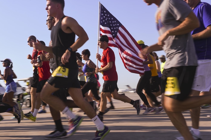 Steven Ralph, Team Red, White and Blue representative, center, runs with the American flag for Joint Base Charleston’s 9th annual Run the Runway here, June 10. Ralph placed third in the age 35 to 39 male bracket with a time of 23:51. 