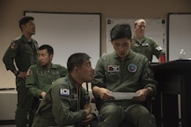Republic of Korea Air Force (ROKAF) Capt. Yeo Myeonghwan, center left, the 20th Tactical Fighter Wing (TFW) escort flight leader out of Seosan Air Base, Korea, speaks with Capt. Lee Min Kyu, center right, a 20th TFW pilot, about their roles in the mission during RED FLAG-Alaska 17-2, June 12, 2017, at Eielson Air Force Base, Alaska. ROKAF's role included playing as an escort for bombers during training. (U.S. Air Force photo by Airman 1st Class Sadie Colbert)
