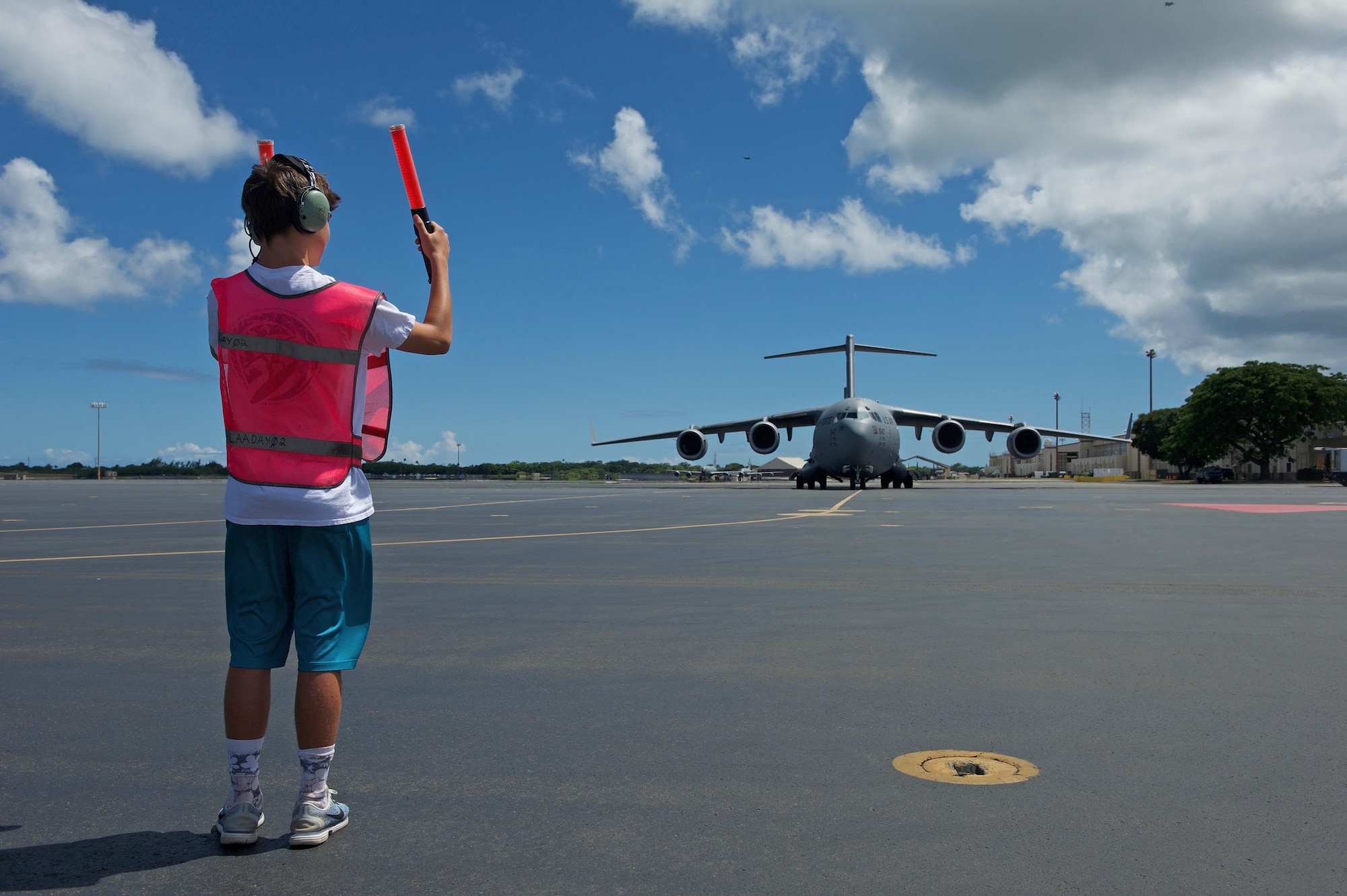 Luke Dillon, son of U.S. Air Force Maj. Gen. Mark Dillon, Pacific Air Forces vice commander, helps marshal a C-17 Globemaster III that his father flew on for his fini flight at Joint Base Pearl Harbor-Hickam, Hawaii, June 12, 2017. With Dillon's retirement approaching, the fini-flight is the capstone event in his flying career. Moments after his arrival, Dillon was greeted by family and friends and soaked in water and champagne to celebrate his Air Force career. (U.S. Air Force photo/Tech. Sgt. Kamaile Chan)