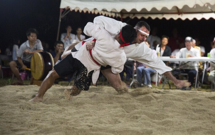 Lt. Col. James Dorlon (right center) slams his opponent to the ground, June 10, 2017, during the annual Henoko Okinawa-Style Sumo Tournament, at Mae-No-Hama Field, in Henoko, Okinawa, Japan. During a bout, competitors try to earn points by making their opponent fall into the dohyo, or sandy pit, without striking or letting go of each other’s belts. The first to gain two points is the victor. Dorlon is a native of Beaverton, Oregon, and the commanding officer of Jungle Warfare Training Center, 3rd Marine Division, III Marine Expeditionary Force. (U.S. Marine Corps photo by Lance Cpl. Andy Martinez)
