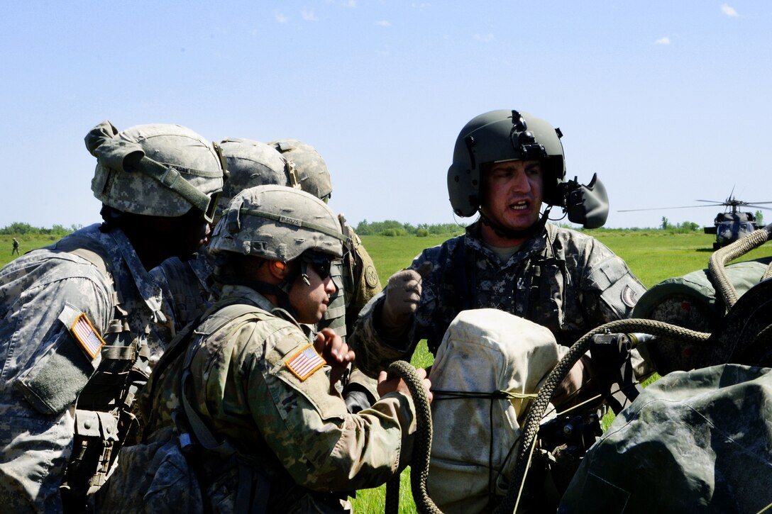 New York Army National Guard Sgt. Nicholas Cook, right, instructs soldiers on how to properly hook a M119A2 howitzer to a UH-60 Black Hawk helicopter at Fort Drum, N.Y., June 8, 2017. Cook is assigned to the 3rd Battalion, 142nd Aviation Division. The soldiers are assigned to the 1st Battalion, 258th Field Artillery. Army National Guard photo by Pfc. Andrew Valenza