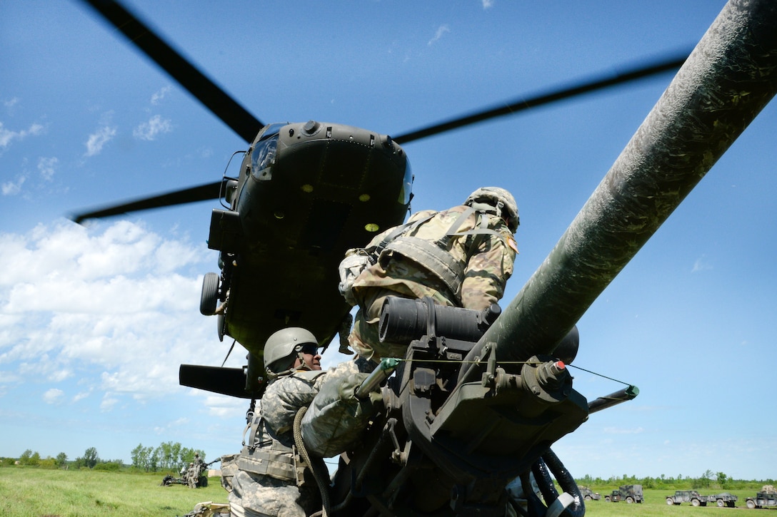 New York Army National Guardsmen prepare to hook up an M119A2 howitzer to a UH-60 Black Hawk helicopter during slingload training at Fort Drum, N.Y., June 8, 2017. Army National Guard photo by Pfc. Andrew Valenza