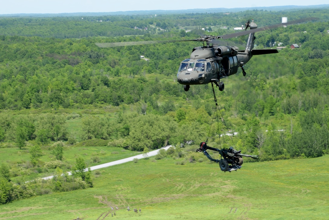 A New York Army National Guard UH-60 Black Hawk helicopter transports an M119A2 howitzer during slingload training at Fort Drum, N.Y., June 8, 2017. The crew is assigned to the 3rd Battalion, 142nd Aviation Division. Army National Guard photo by Pfc. Andrew Valenza