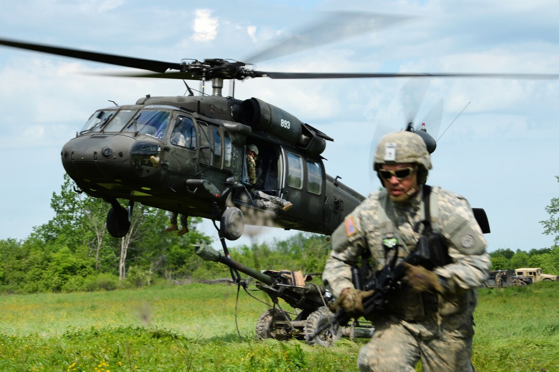 A New York Army National Guardsman rushes away as a UH-60 Black Hawk helicopter prepares to lift off after being slingloaded with an M119A2 howitzer during training at Fort Drum, N.Y., June 9, 2017. Army National Guard photo by Pfc. Andrew Valenza