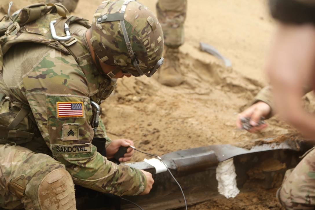 Army Sgt. Juan Sandoval sets an M152 booster assembly onto a C-4 explosive charge during demolition training at the Bemowo Piskie training area in Poland, June 7, 2017. Army photo by Spc. Samuel Brooks 