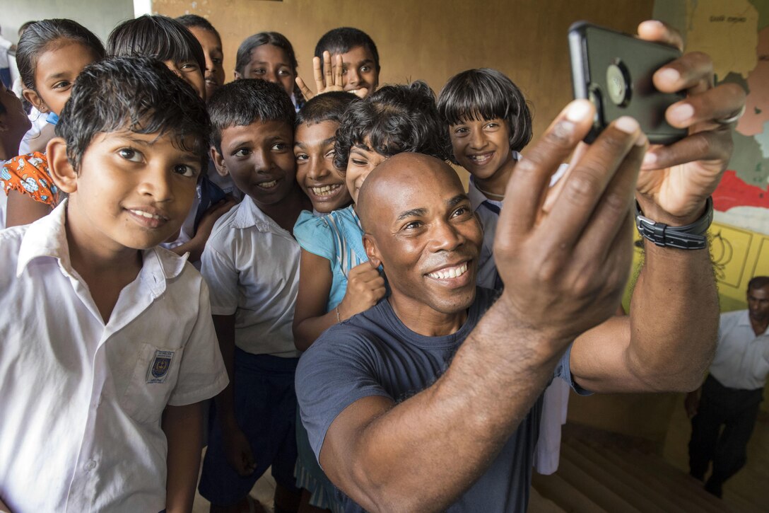 Navy Capt. Lex Walker, commodore of Destroyer Squadron 7, takes photos with students at the Mallika Nawodya School in Sri Lanka during a community engagement event in support of humanitarian assistance operations in the wake of severe flooding and landslides that devastated many regions of the country near Galle, Sri Lanka, June 14, 2017. Recent heavy rainfall brought by a southwestern monsoon triggered flooding and landslides throughout the country, displacing thousands of people and causing significant damage to homes and buildings. Navy photo by Petty Officer 2nd Class Joshua Fulton